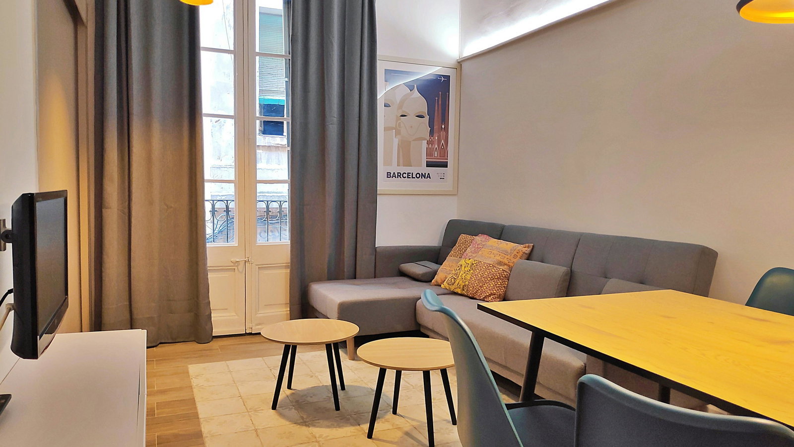 Unwind in the living area, where modern furnishings meet classic Barcelona charm with a small balcony overlooking the street.