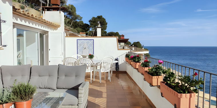 The spacious terrace of this penthouse apartment boasts stunning sea views and offers a tranquil escape. Relax on the comfortable sofa while enjoying the fresh air and sunshine, or dine al fresco at the table surrounded by the lush greenery.