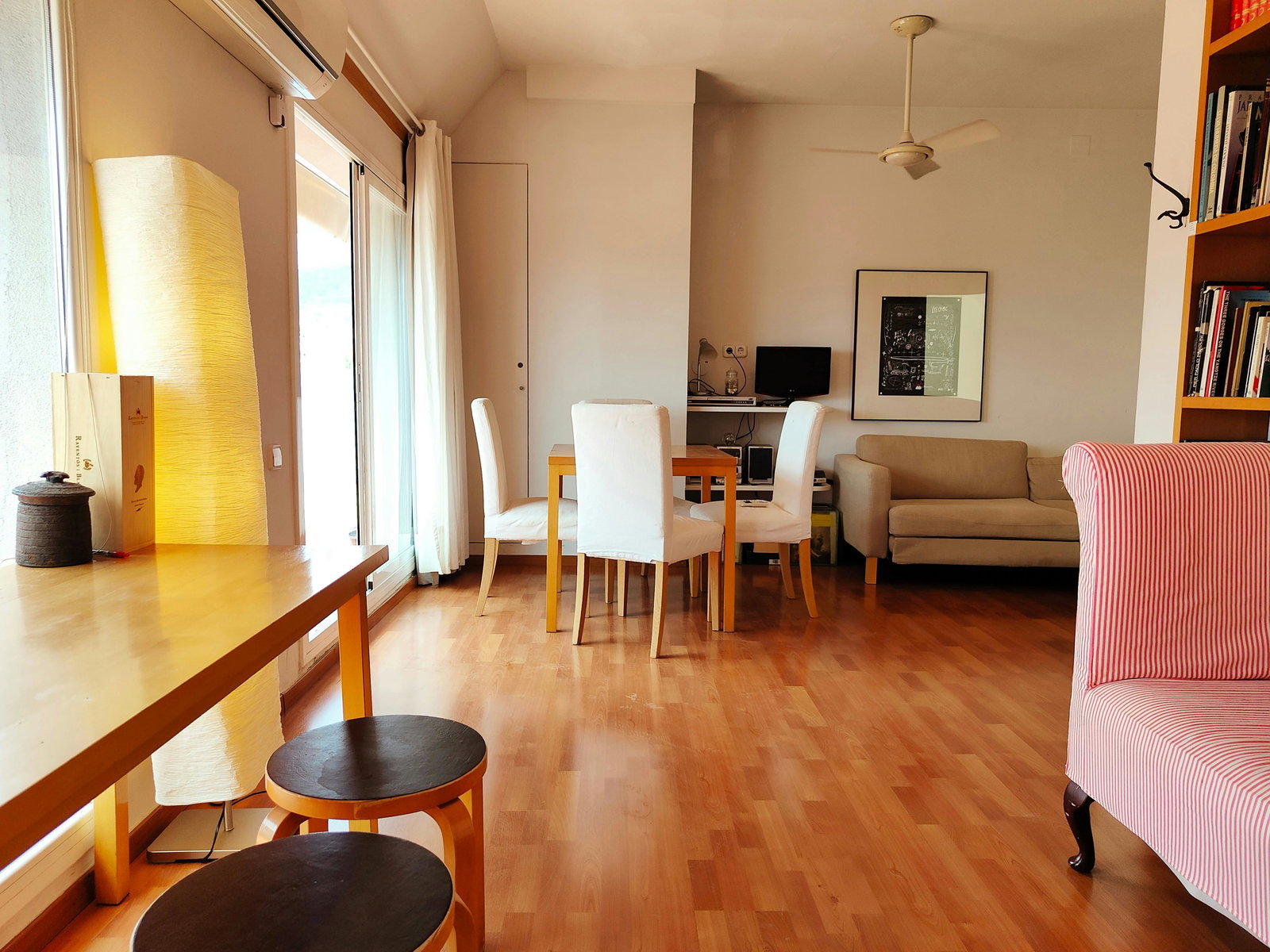 Bright, open-plan living and dining area with warm hardwood floors and abundant natural light from the terrace doors.