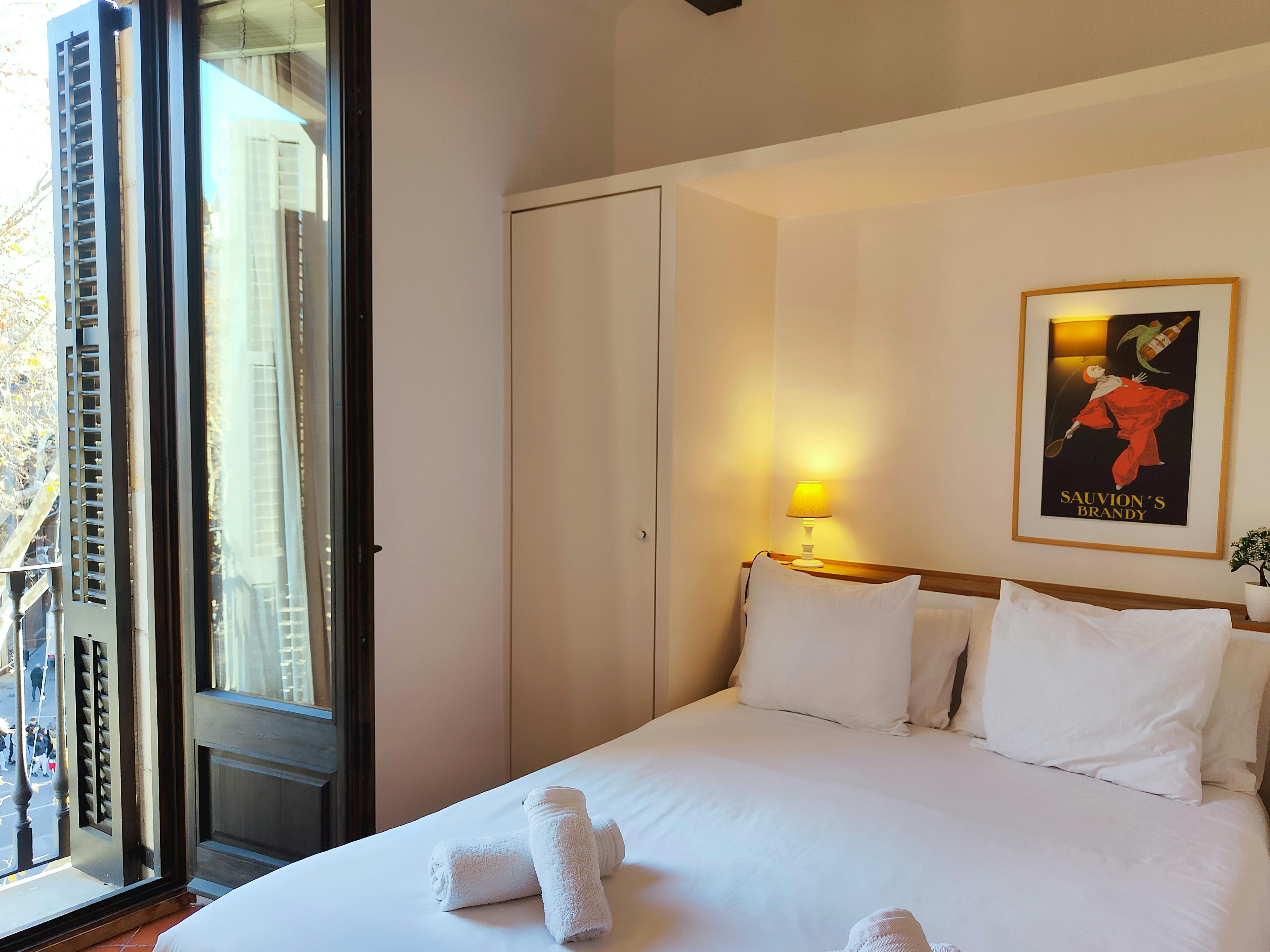 Natural light fills this inviting room, featuring a comfortable queen bed and access to a french balcony overlooking Las Ramblas.  Enjoy the vibrant energy of Barcelona right from your doorstep.