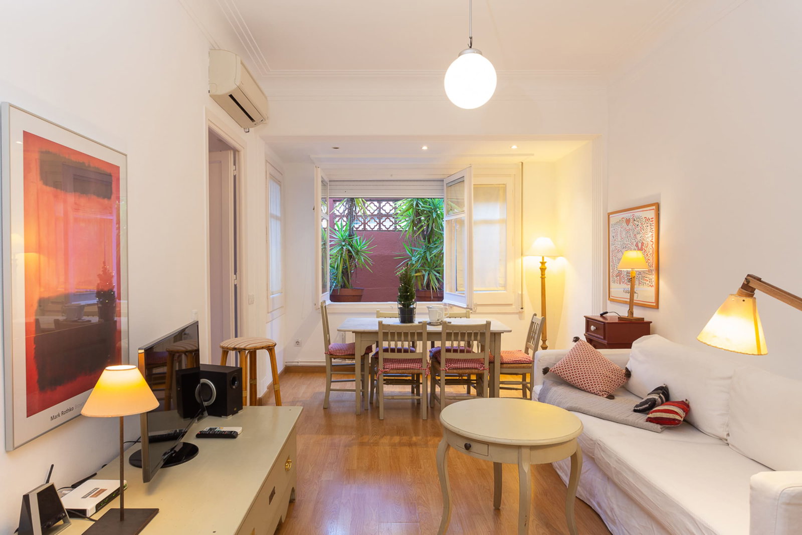 Relax in the bright, inviting living area, where warm wood floors and comfortable furnishings create a cozy atmosphere for your stay.