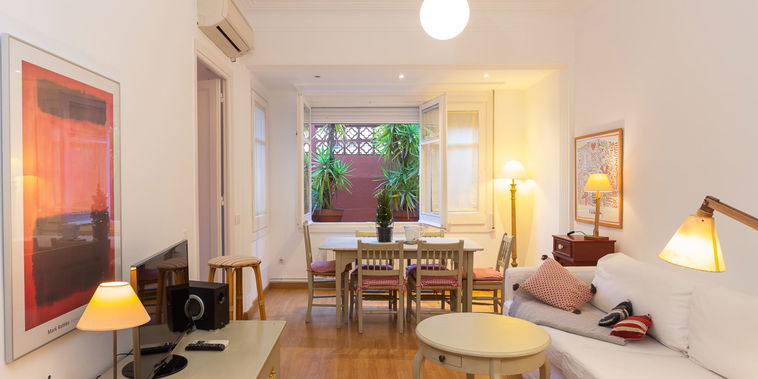 Relax in the bright, inviting living area, where warm wood floors and comfortable furnishings create a cozy atmosphere for your stay.