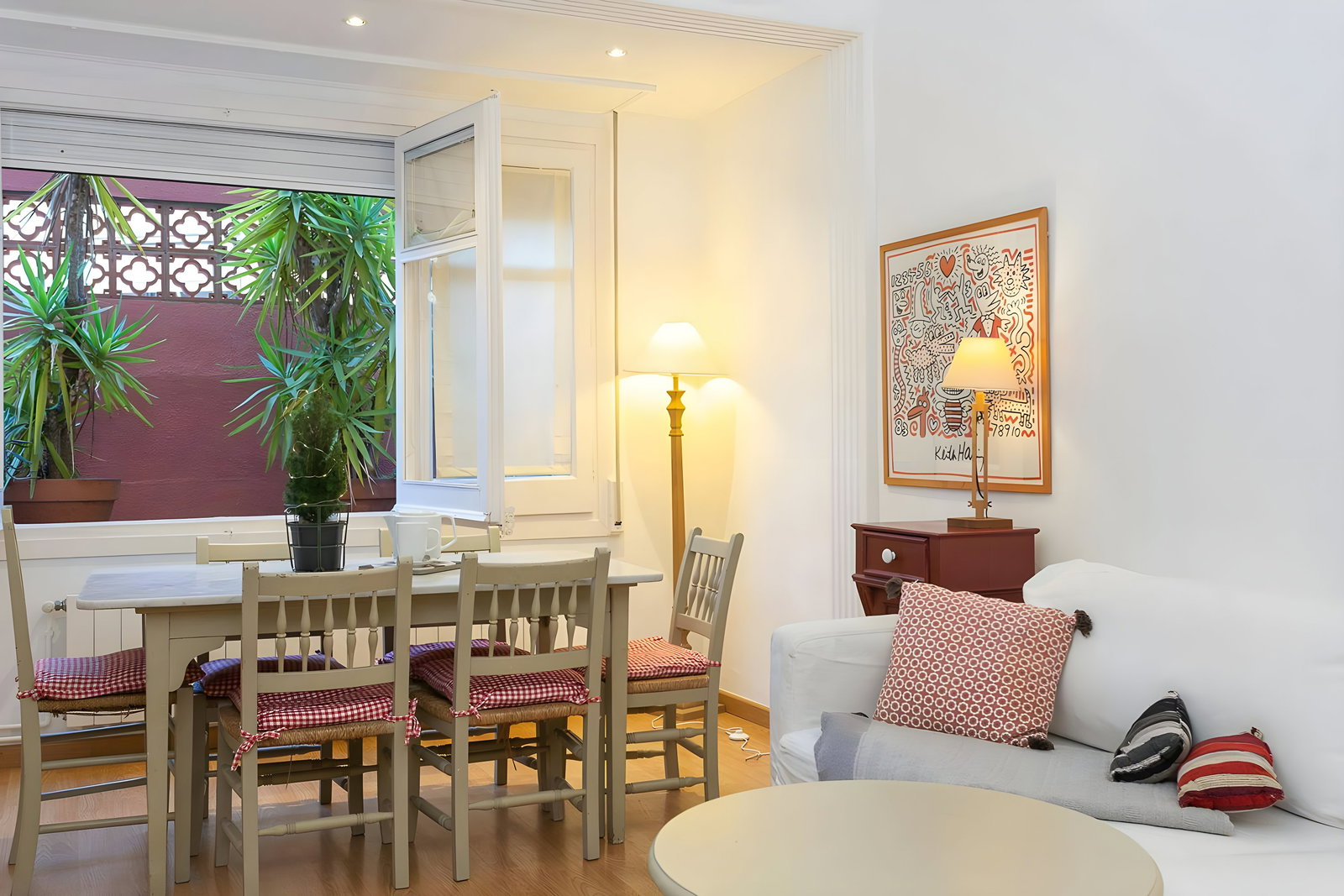 Gather for a meal in the bright dining area, which opens onto a small terrace lush with greenery.