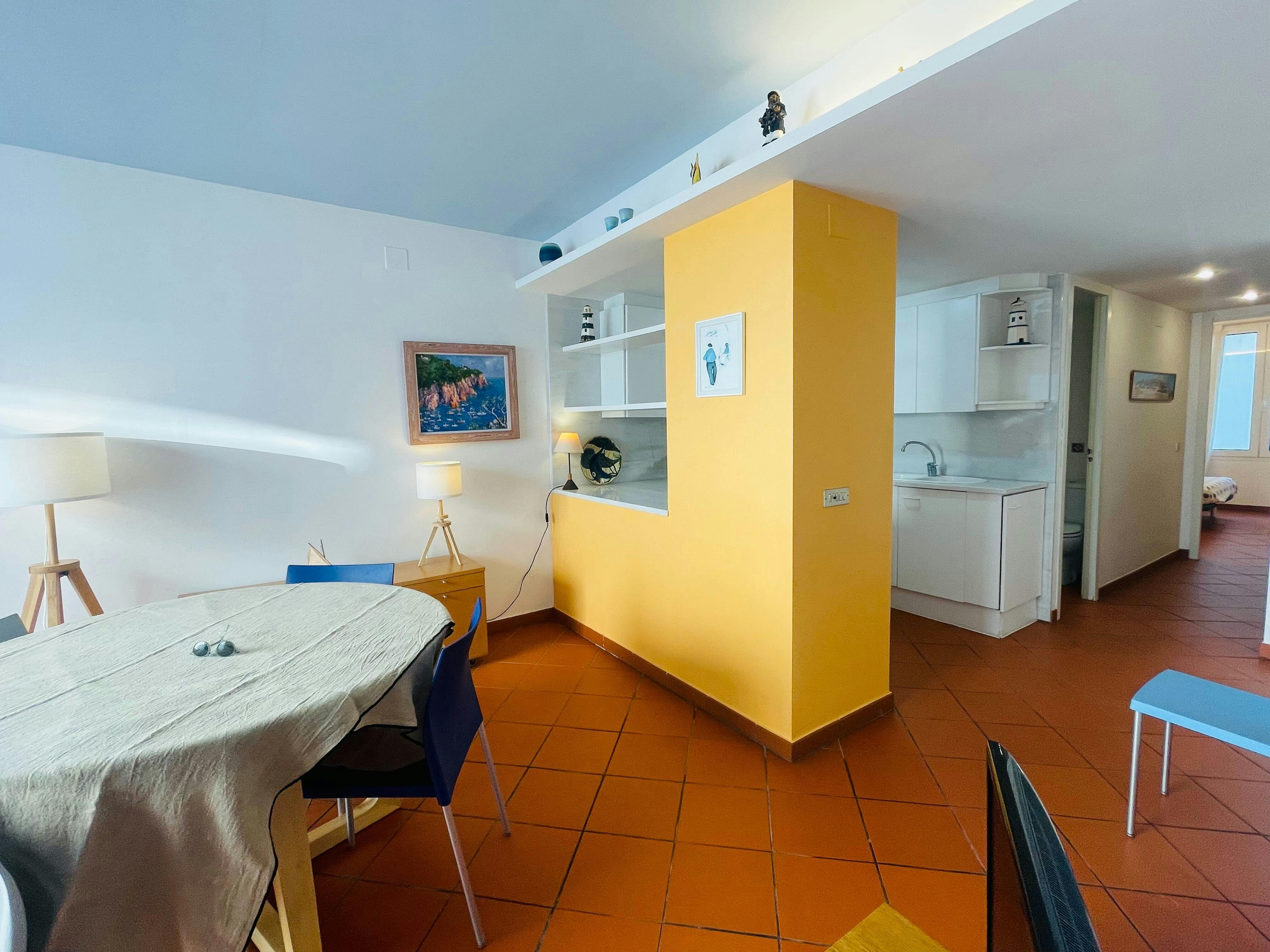 Bathed in natural light, the open-plan living and dining area creates a cheerful atmosphere with its vibrant color palette of sunny yellow and terracotta.
