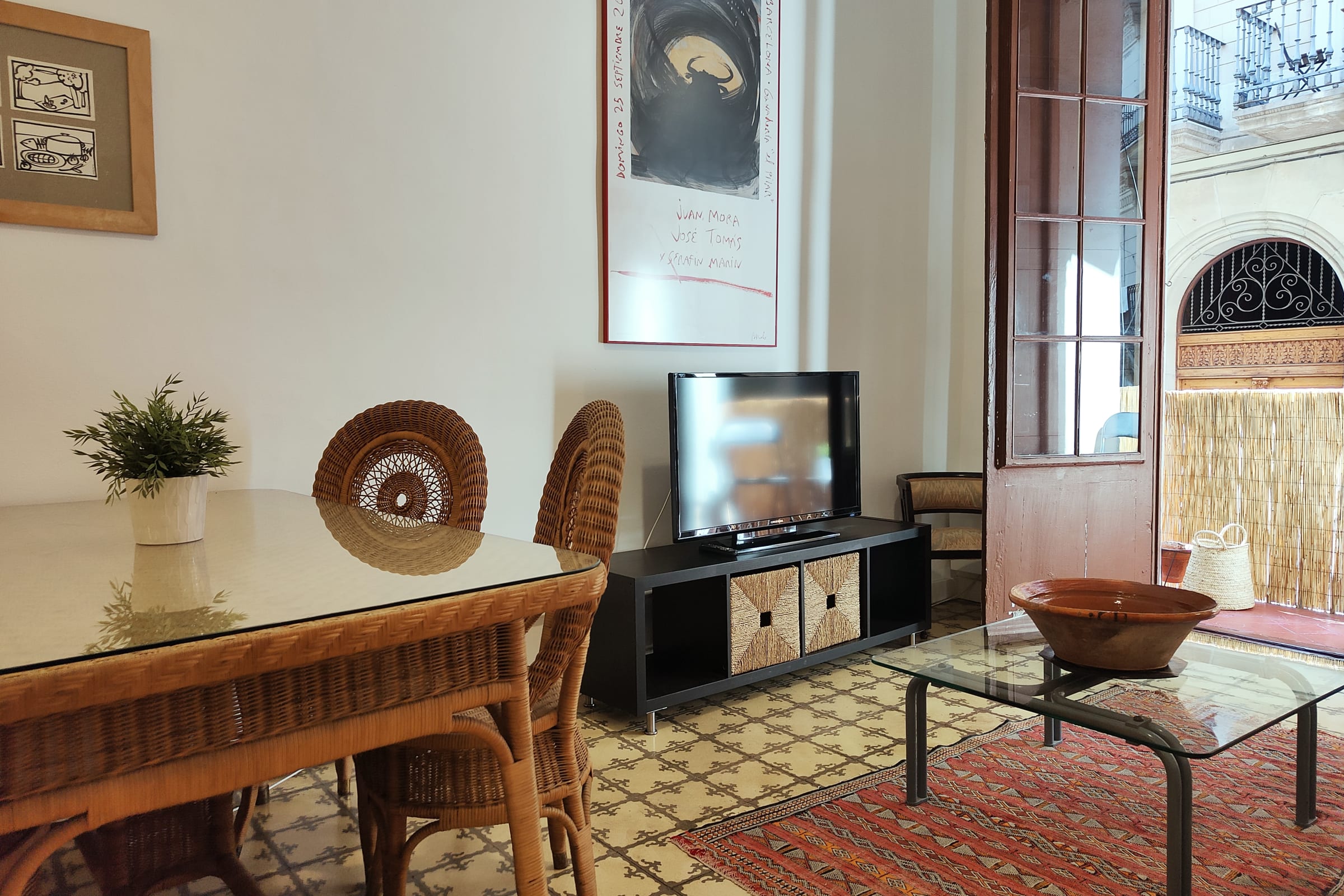The open floor plan of this apartment creates a sense of spaciousness, with the kitchen seamlessly flowing into the dining and living areas. The  wicker furniture adds warmth and texture, creating a welcoming atmosphere.  This is a great spot to relax after a day of exploring Barcelona.