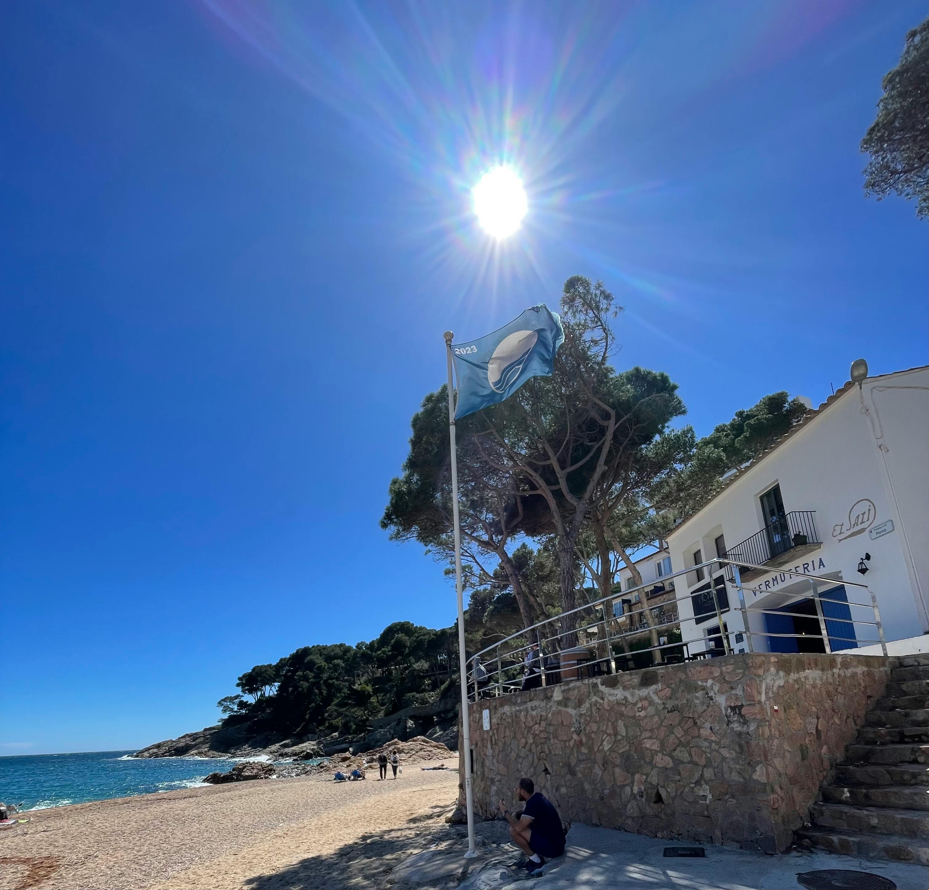 The townhouse is located just steps from the beach, offering stunning views of the clear blue water and the surrounding hills.