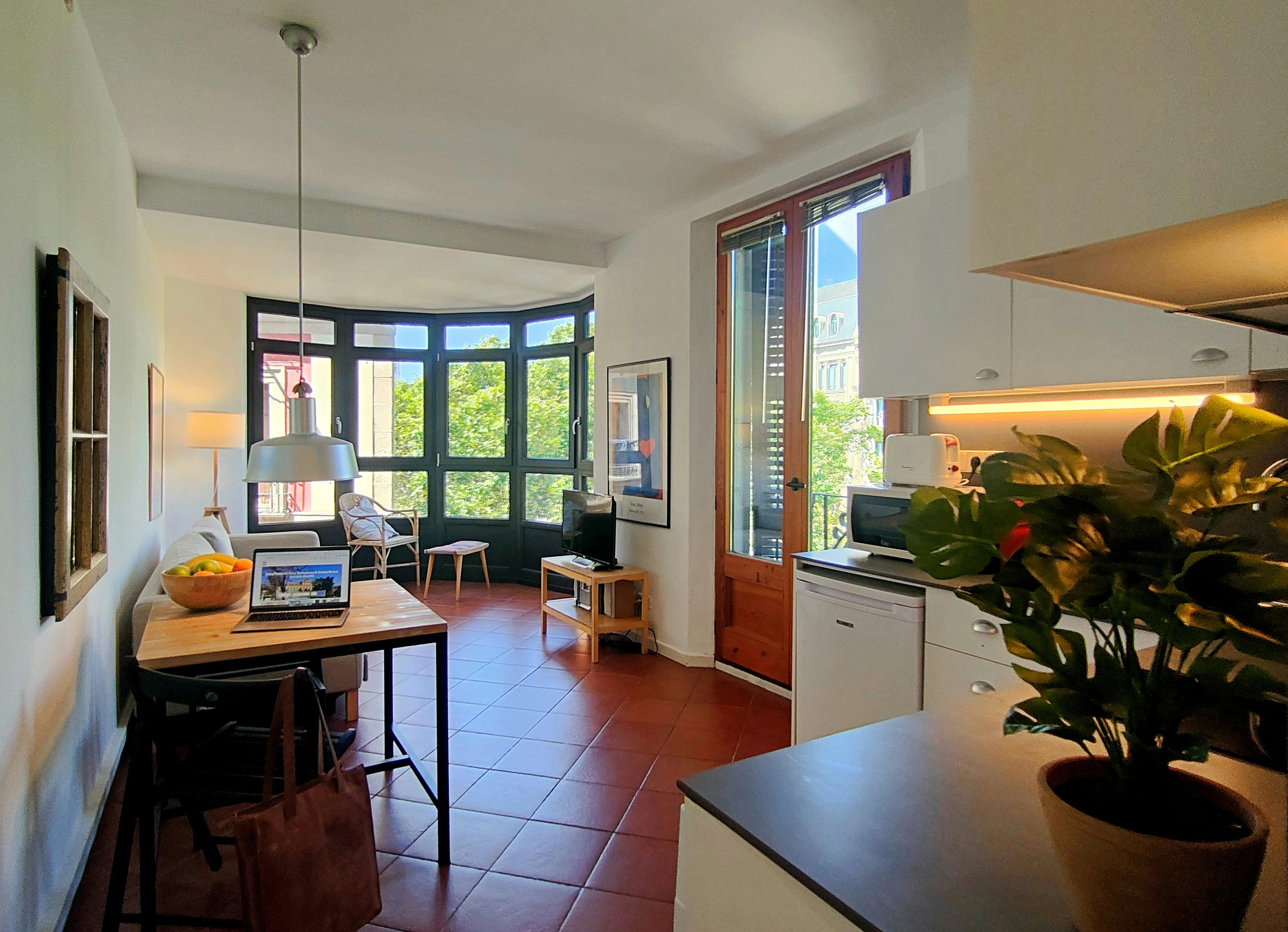 The open-plan living space features a large bay window offering natural light and views of the bustling La Rambla.