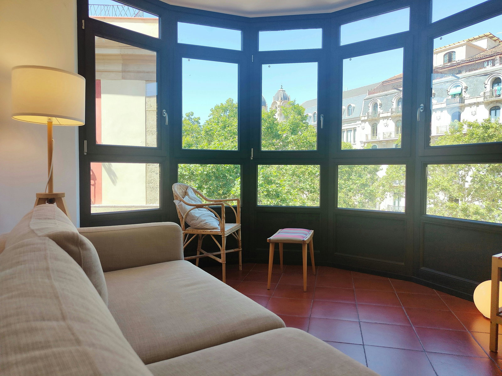 The living room is bathed in natural light streaming through a large bay window offering stunning views of the city.