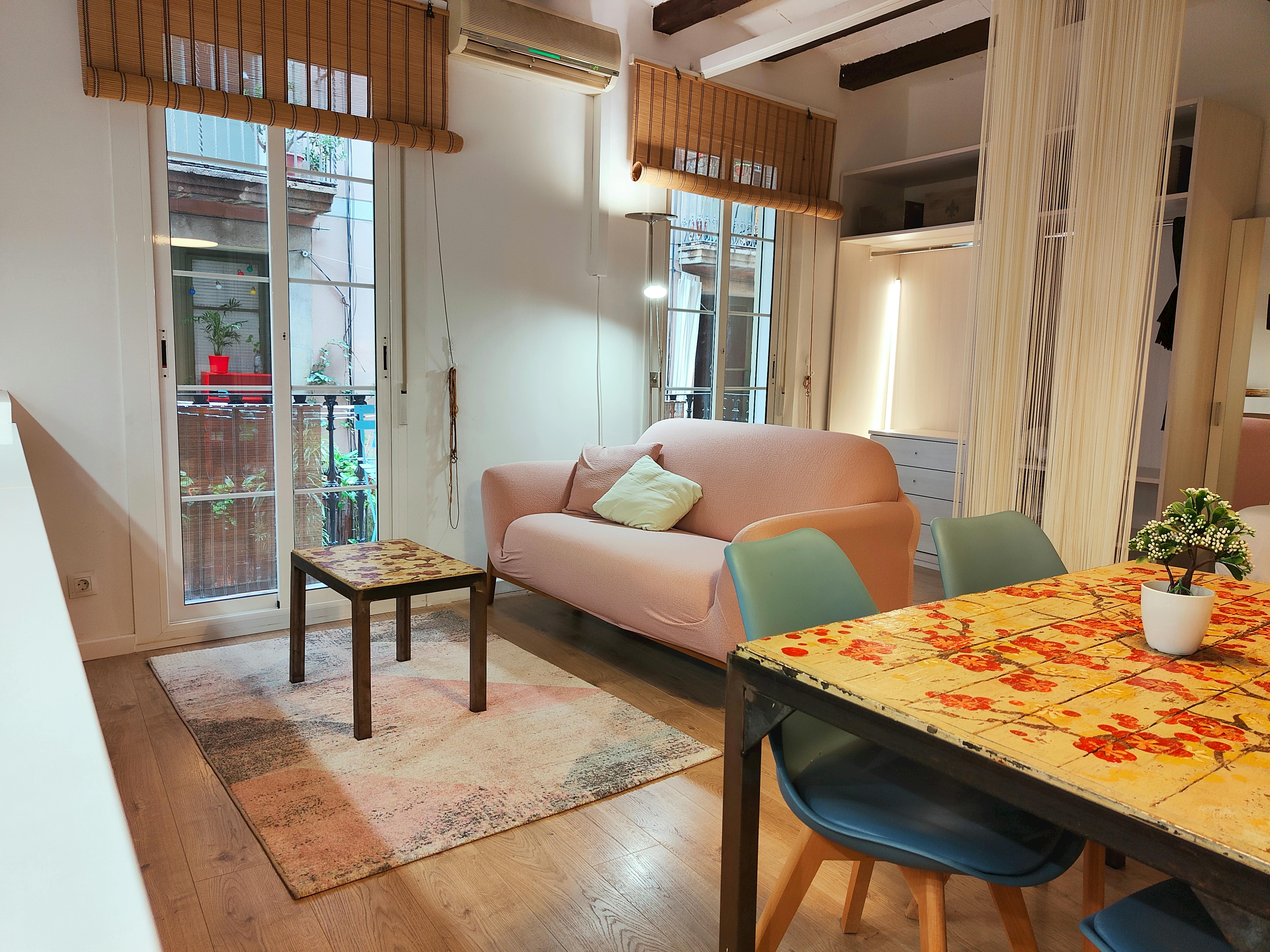 The dining area features a wooden table surrounded by four chairs.  A glimpse of the modern kitchen can be seen in the background, with its wooden cabinets and sleek appliances.