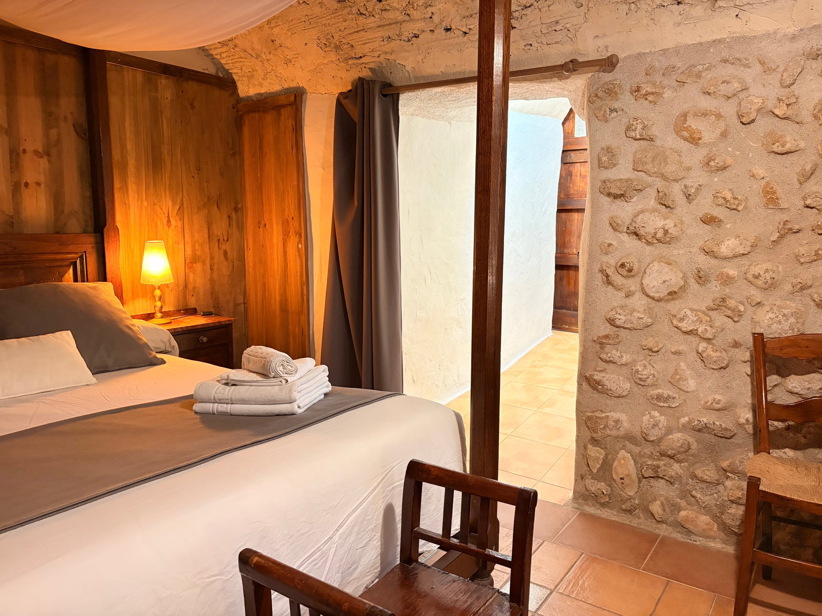 Retreat to the cozy bedroom, where rustic charm meets comfort. The room features an exposed stone wall and warm wood accents, creating a tranquil and historic atmosphere for a restful night's sleep.