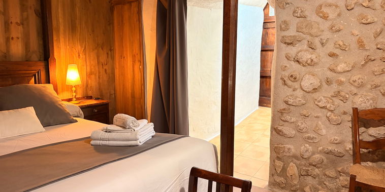 Refúgiese en este acogedor dormitorio, donde las paredes de piedra vista y los muebles de madera crean un ambiente rústico y cálido para un buen descanso.