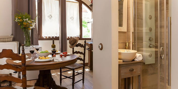Enjoy an intimate meal at the rustic wooden dining table, bathed in natural light from the charming arched window.