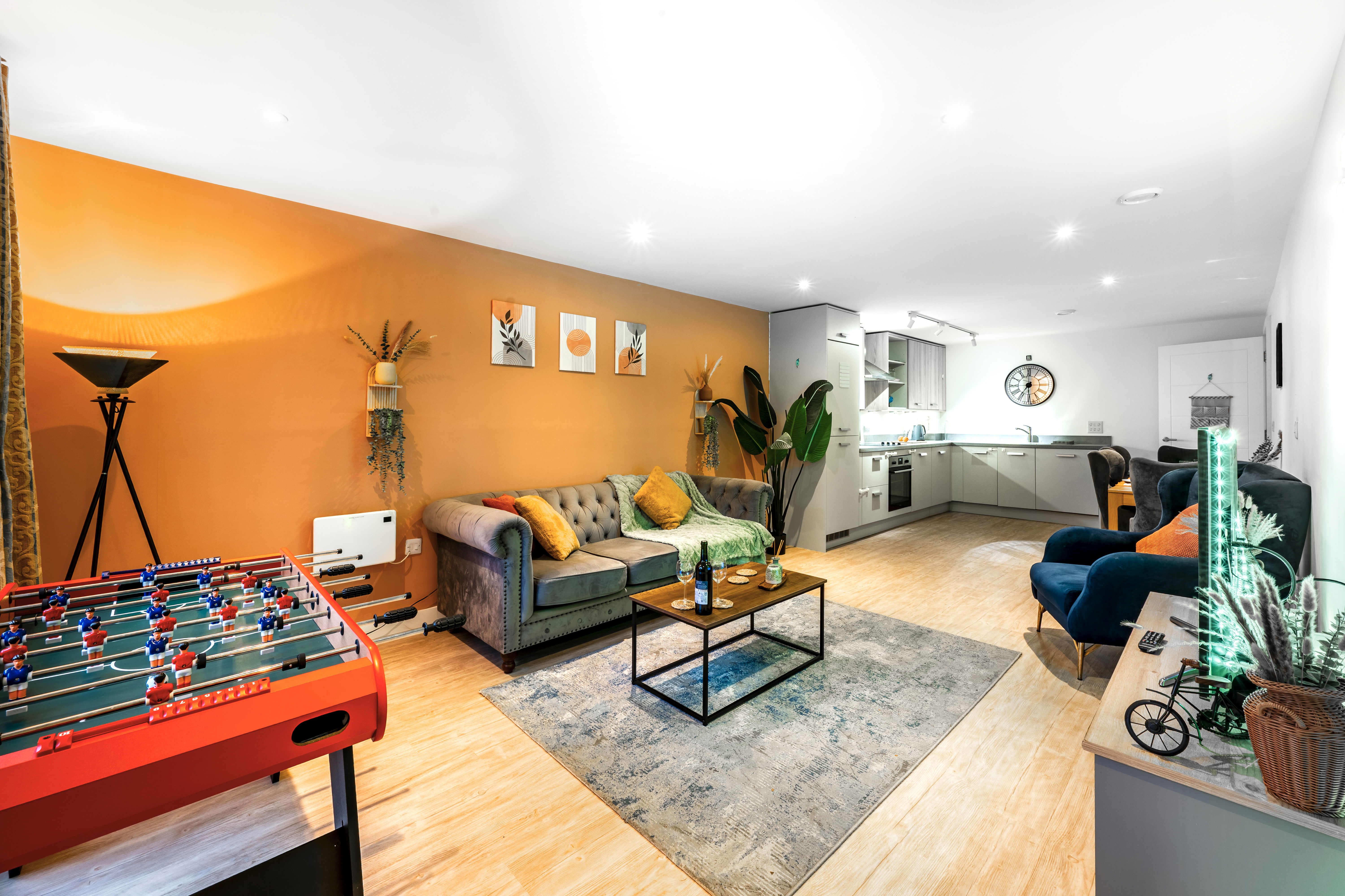 A spacious, beautifully designed living room with a cosy sofa, two velvet armchairs and warm lighting. Large windows bring in natural light, and the room’s modern décor creates a calm, comfortable atmosphere that makes you feel instantly at home.