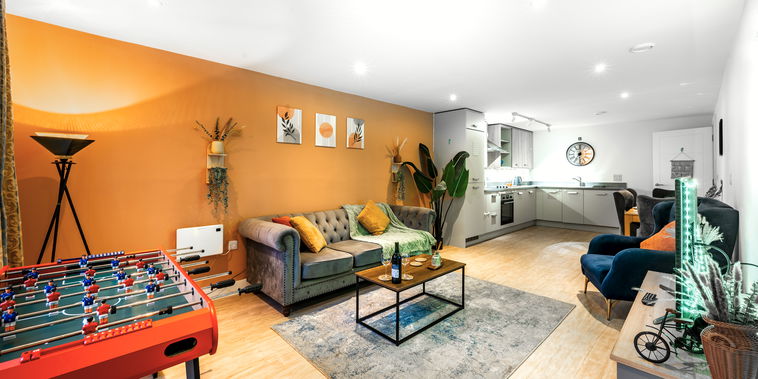 A spacious, beautifully designed living room with a cosy sofa, two velvet armchairs and warm lighting. Large windows bring in natural light, and the room’s modern décor creates a calm, comfortable atmosphere that makes you feel instantly at home.