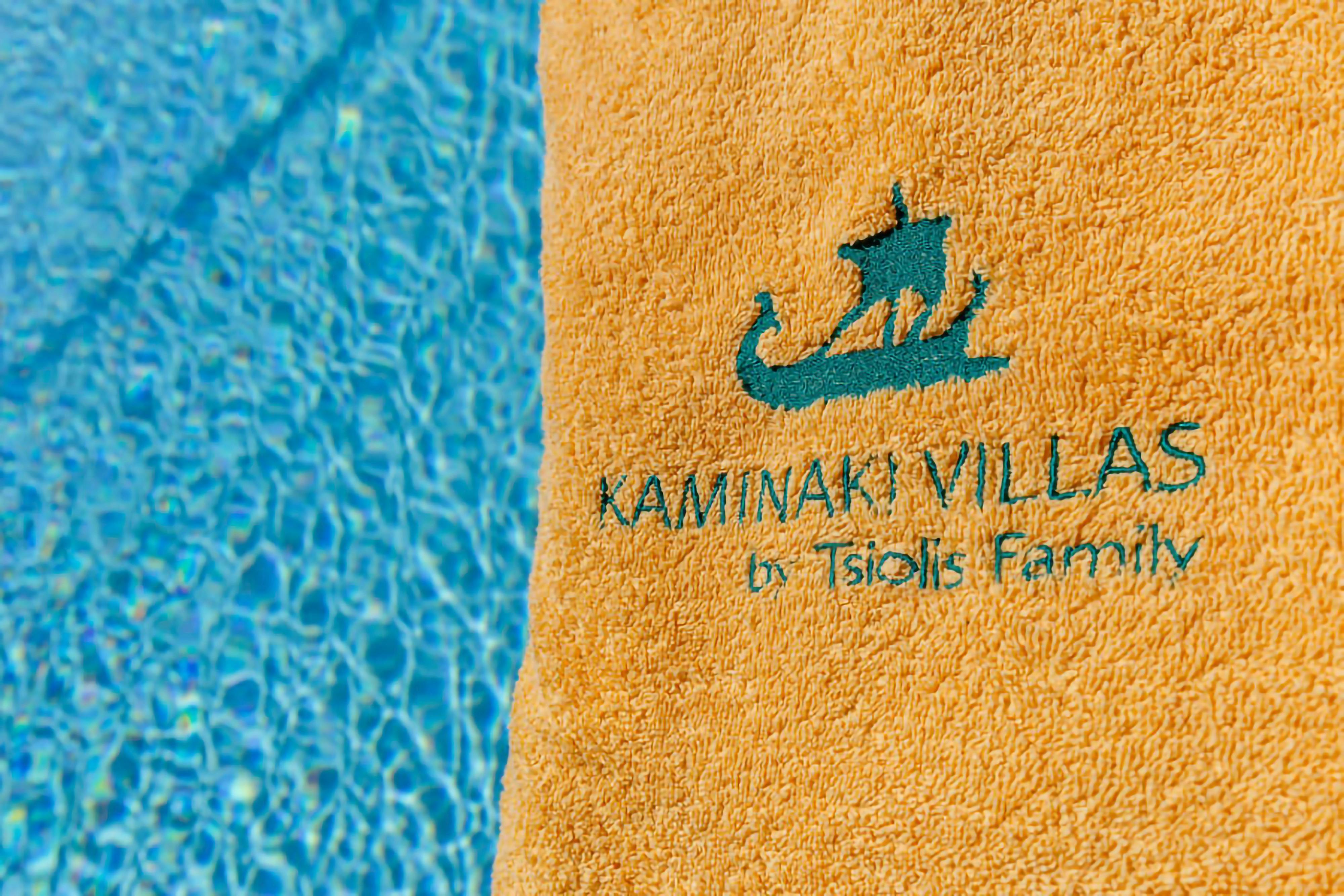 The inviting turquoise waters of the shared pool beckon guests to unwind and enjoy the warmth of the Corfu sun.  Details like the personalized towel hint at the thoughtful touches that await within this tranquil villa.