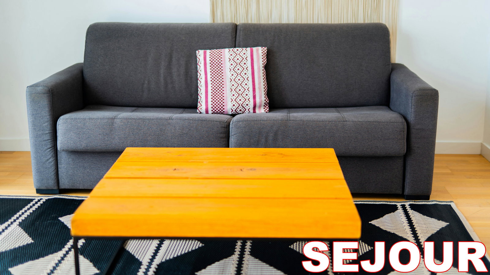 A bright yellow coffee table pops against the sleek grey sofa in this chic living space.  The modern aesthetic is complemented by a graphic rug, creating a welcoming area for relaxation and socializing.