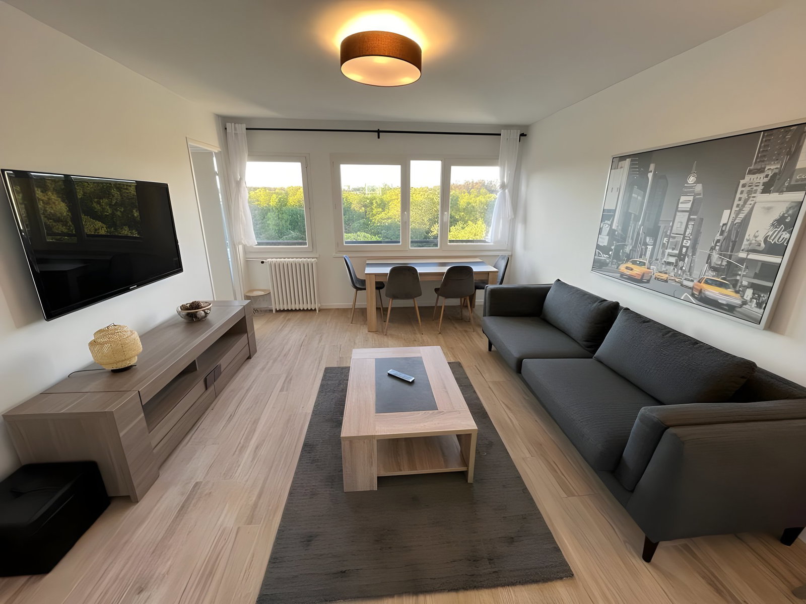 Living room with sofa, coffee table, TV stand, TV, dining area with dining table and 4 chairs