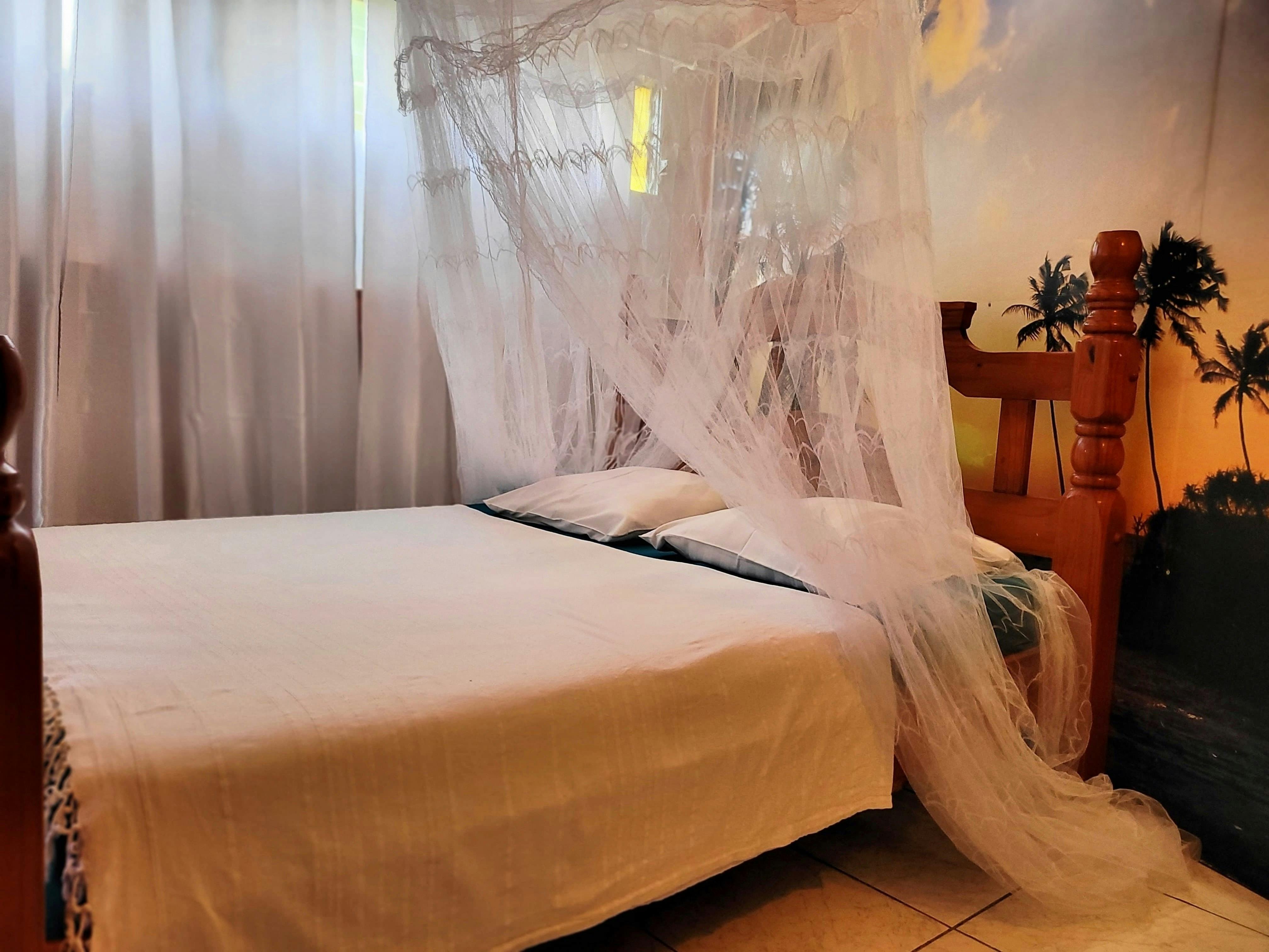 Chambre climatisée avec lit king size 180x200, moustiquaire, dressing et accès direct à la salle d’eau pour un confort optimal.