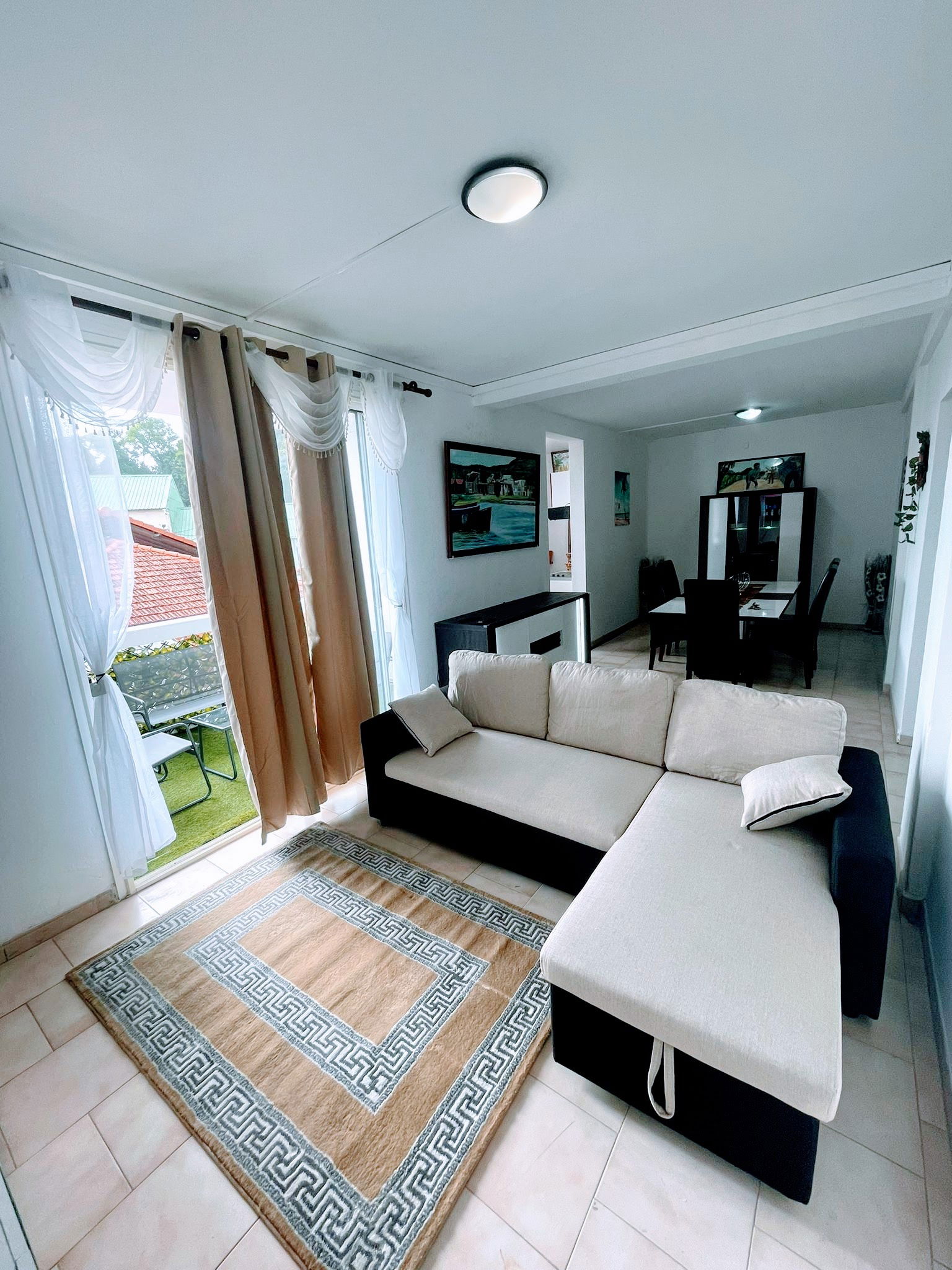 Salon avec grand canapé et télévision, idéal pour se détendre. Profitez d’un espace lumineux ouvrant directement sur le balcon pour un moment agréable en toute sérénité.