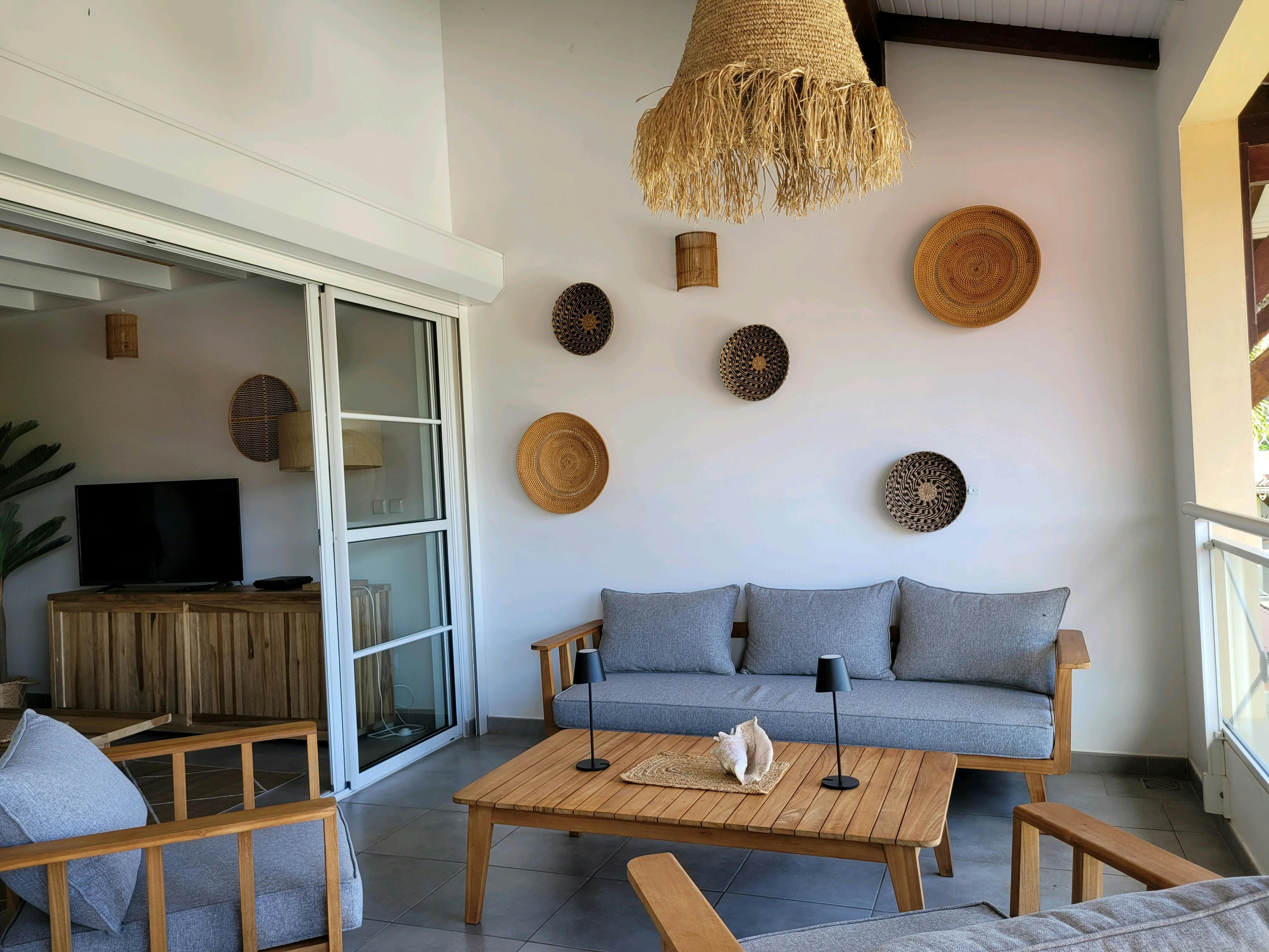 Salon extérieur sur balcon de 20 m² avec grand canapé et deux fauteuils confortables, parfait pour se détendre face à la mer dans une ambiance douce et décontractée.