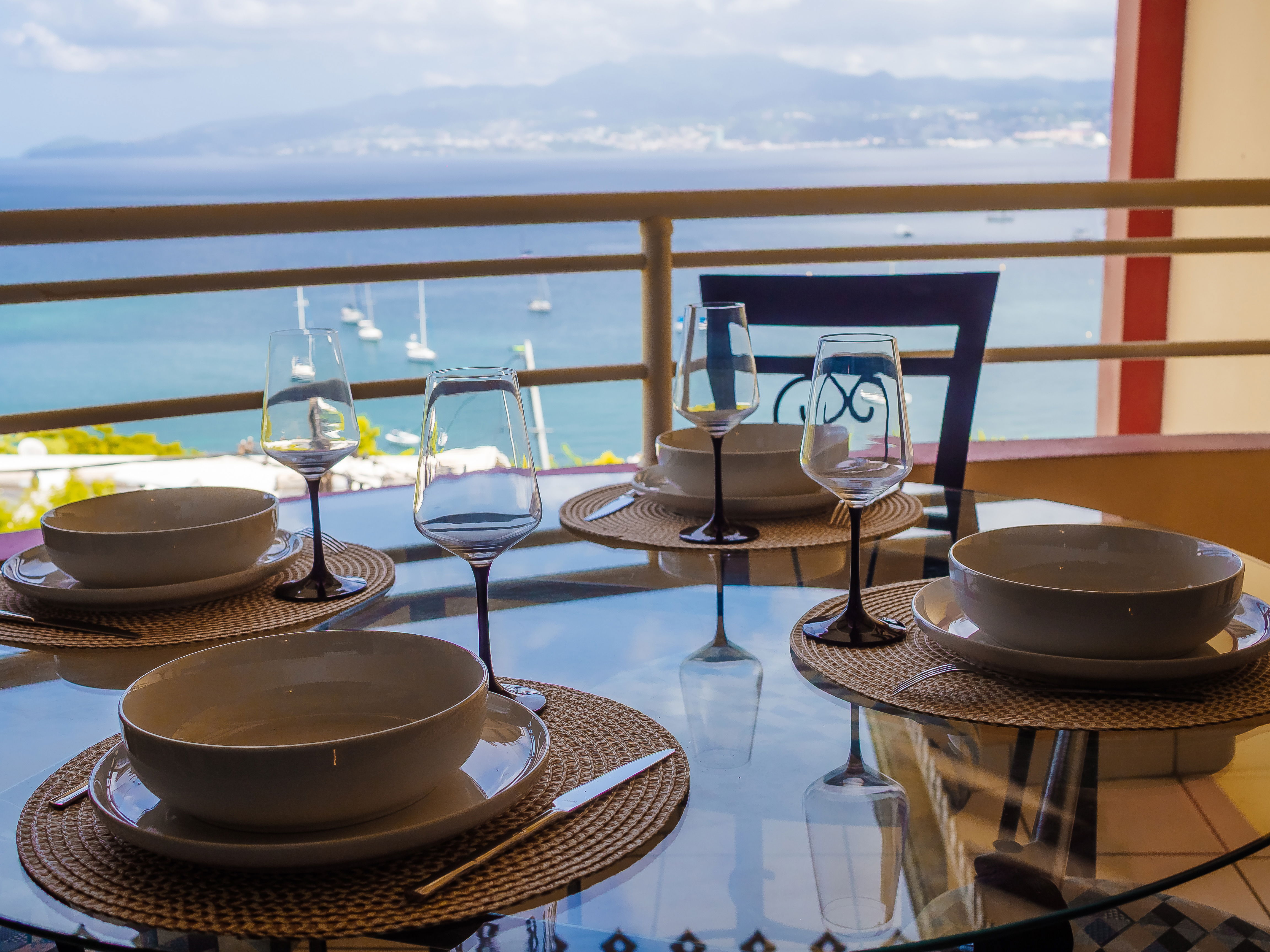 Cuisine astucieusement aménagée sur le balcon avec table et 4 chaises. Profitez d’un repas face à la baie de Fort-de-France, un panorama inoubliable.