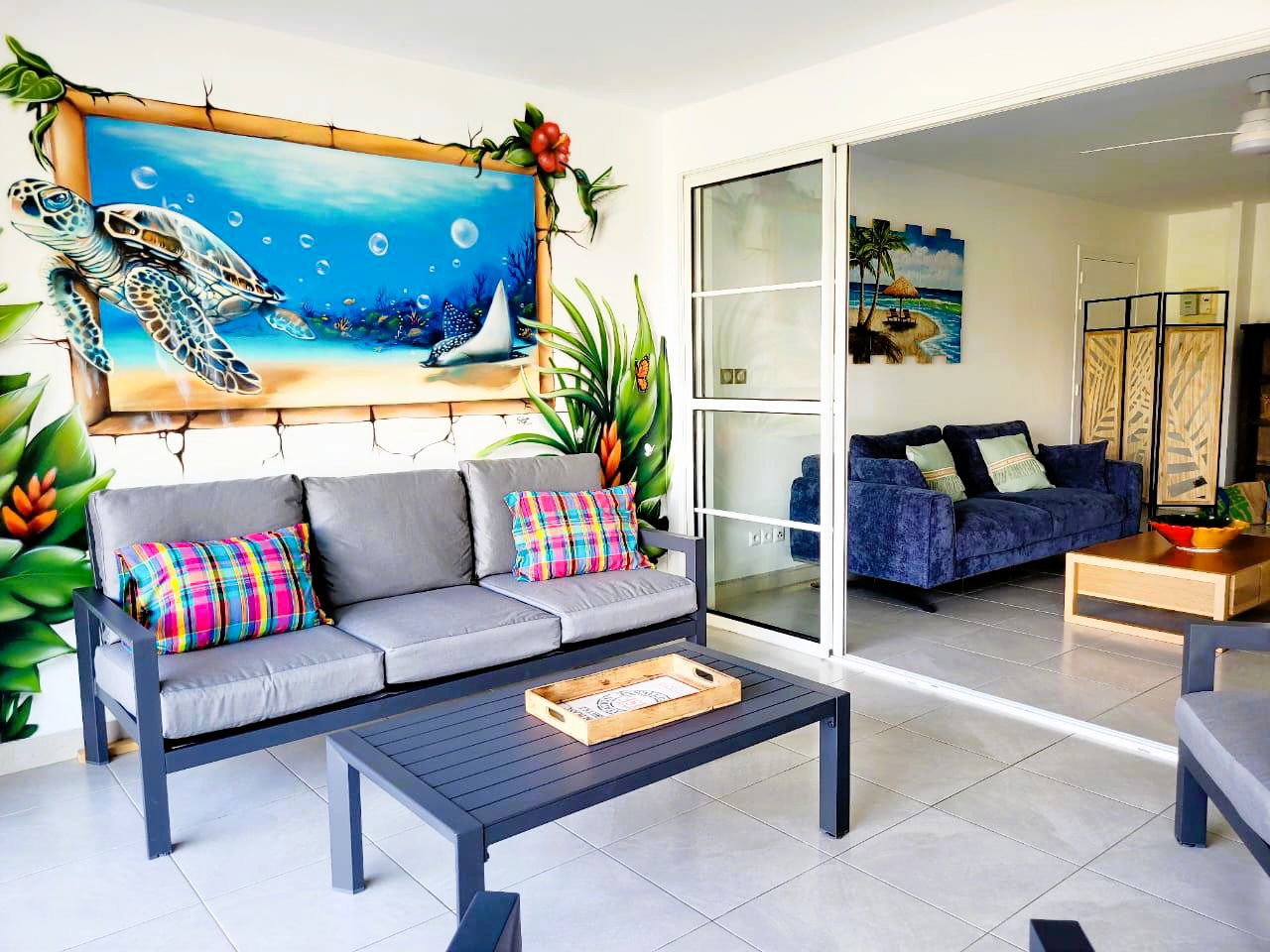 Salon extérieur couvert, idéal pour se détendre à l’ombre. Ventilateur au plafond pour un confort optimal et espace convivial pour profiter pleinement de la terrasse.