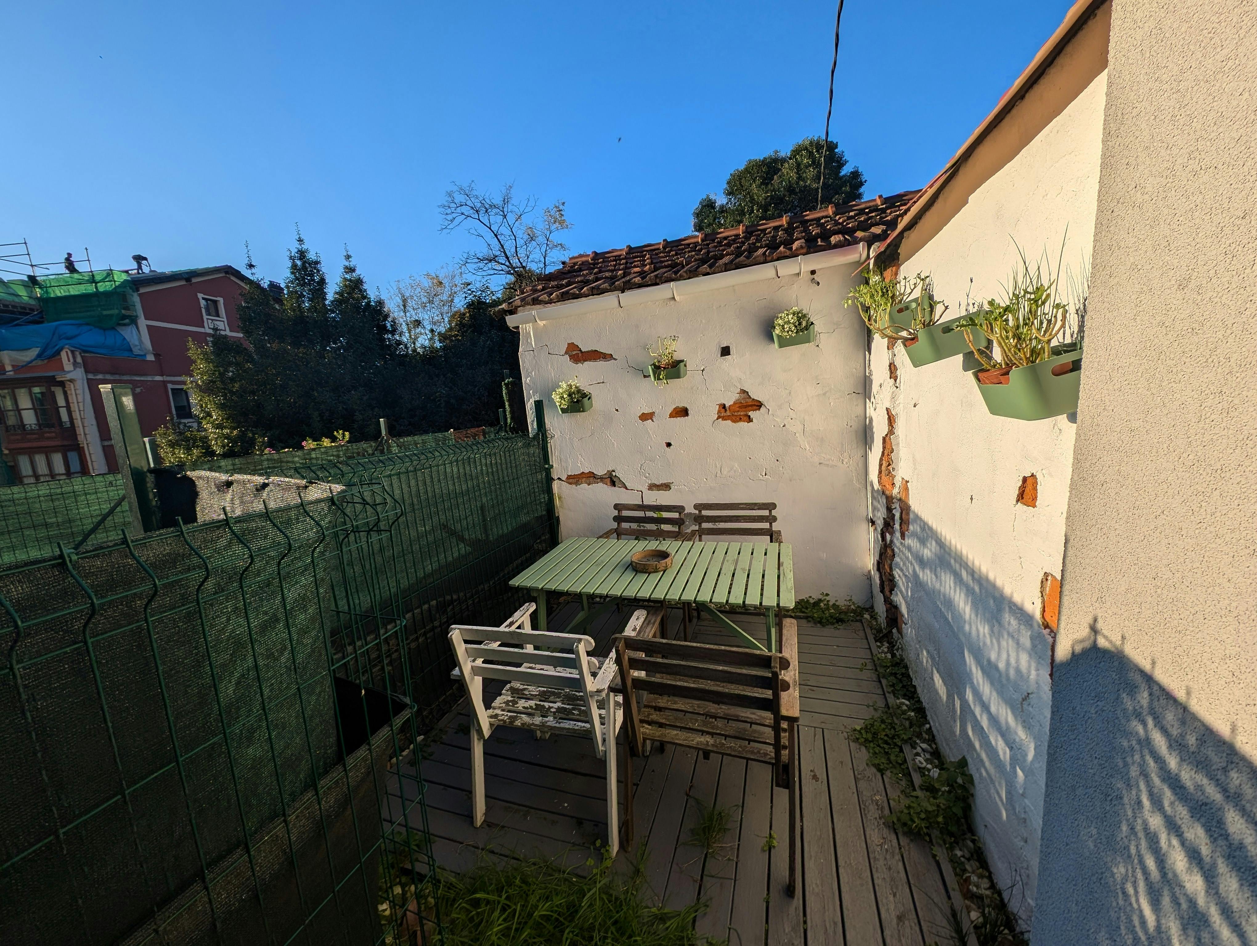 Dappled sunlight dances across the wooden deck of this charming private terrace, inviting you to relax and unwind.  With its weathered charm and secluded ambiance, this urban oasis offers a peaceful retreat in the heart of the city.