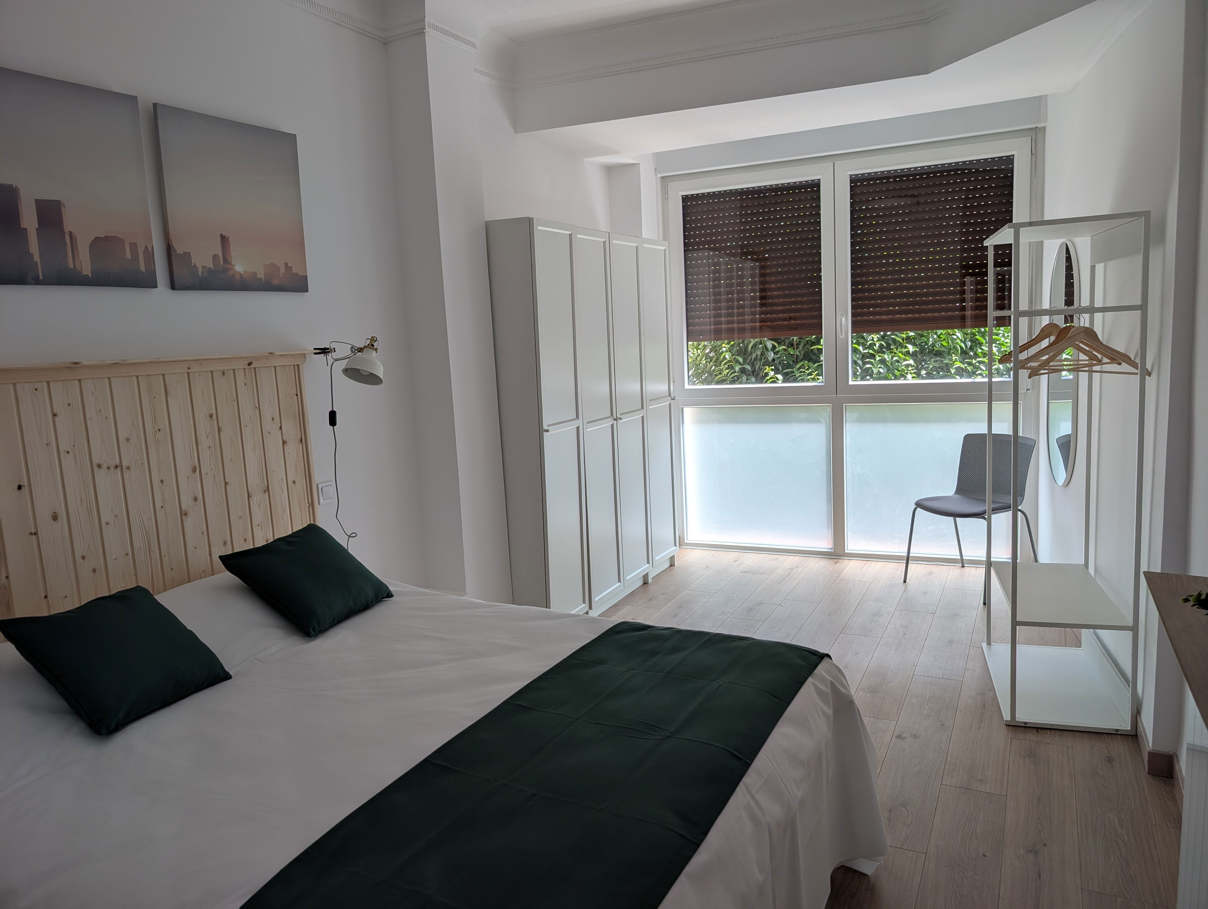 Unwind in this bright, modern bedroom featuring a comfortable queen bed and natural wood accents. Enjoy leafy views from the large window.