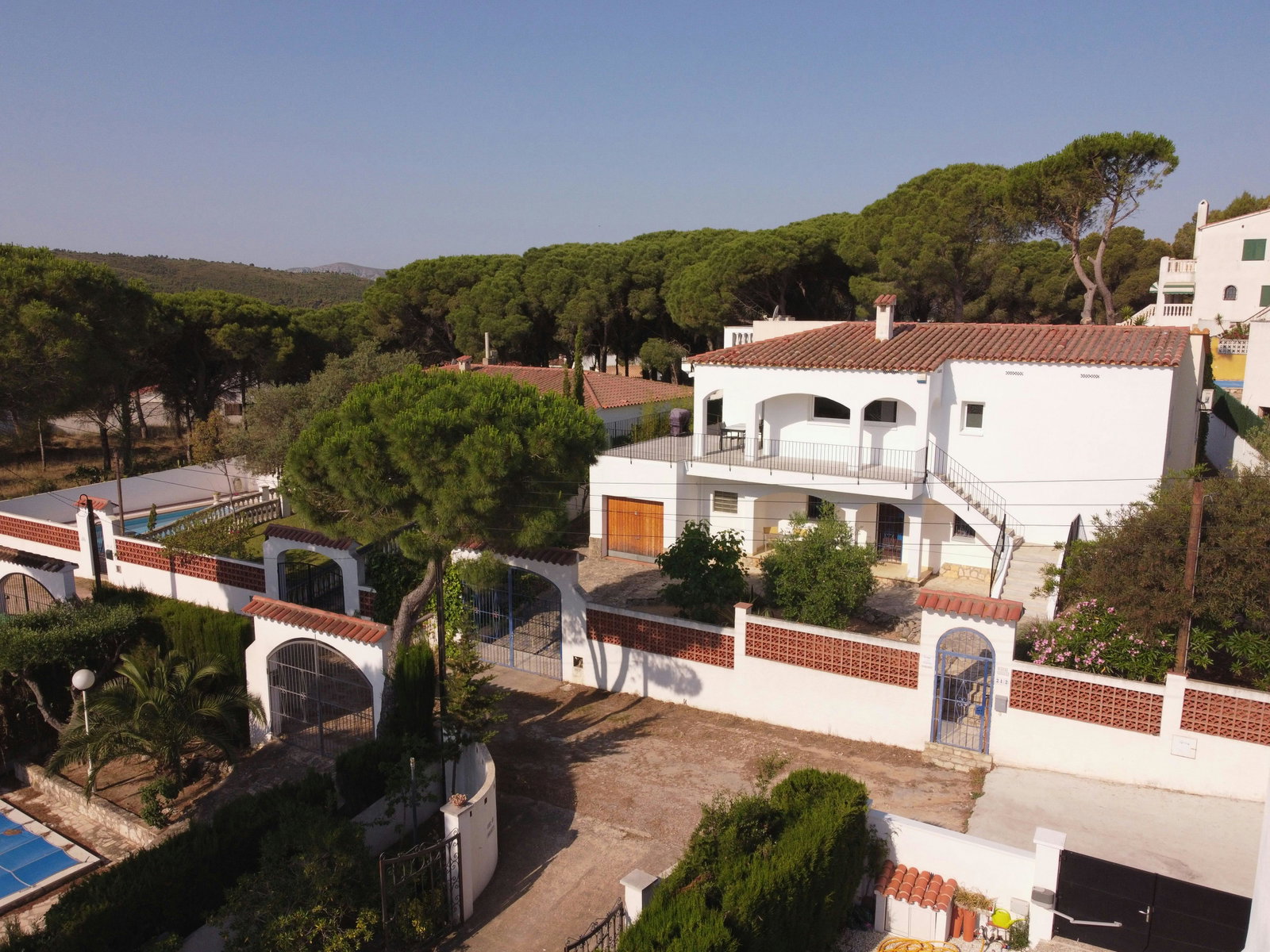 Weiße Villa im mediterranen Stil, umgeben von Pinien. Ihre große Dachterrasse lädt zum Entspannen im Freien ein.