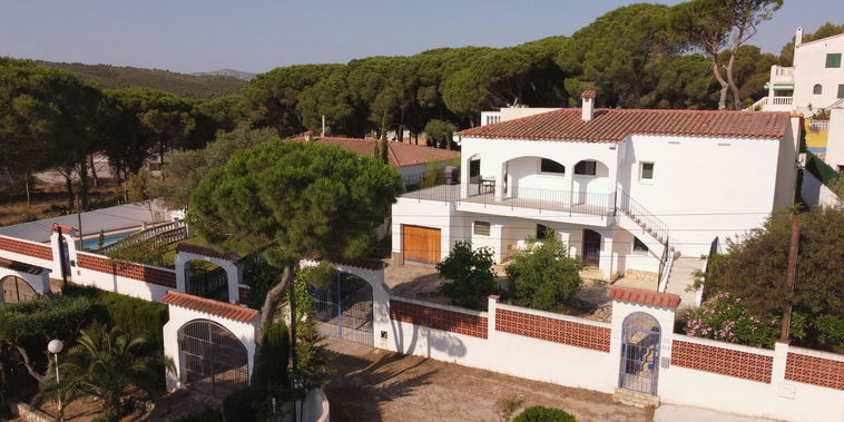 Villa blanca de estilo mediterráneo rodeada de pinos. Su gran terraza superior invita a relajarse al aire libre.