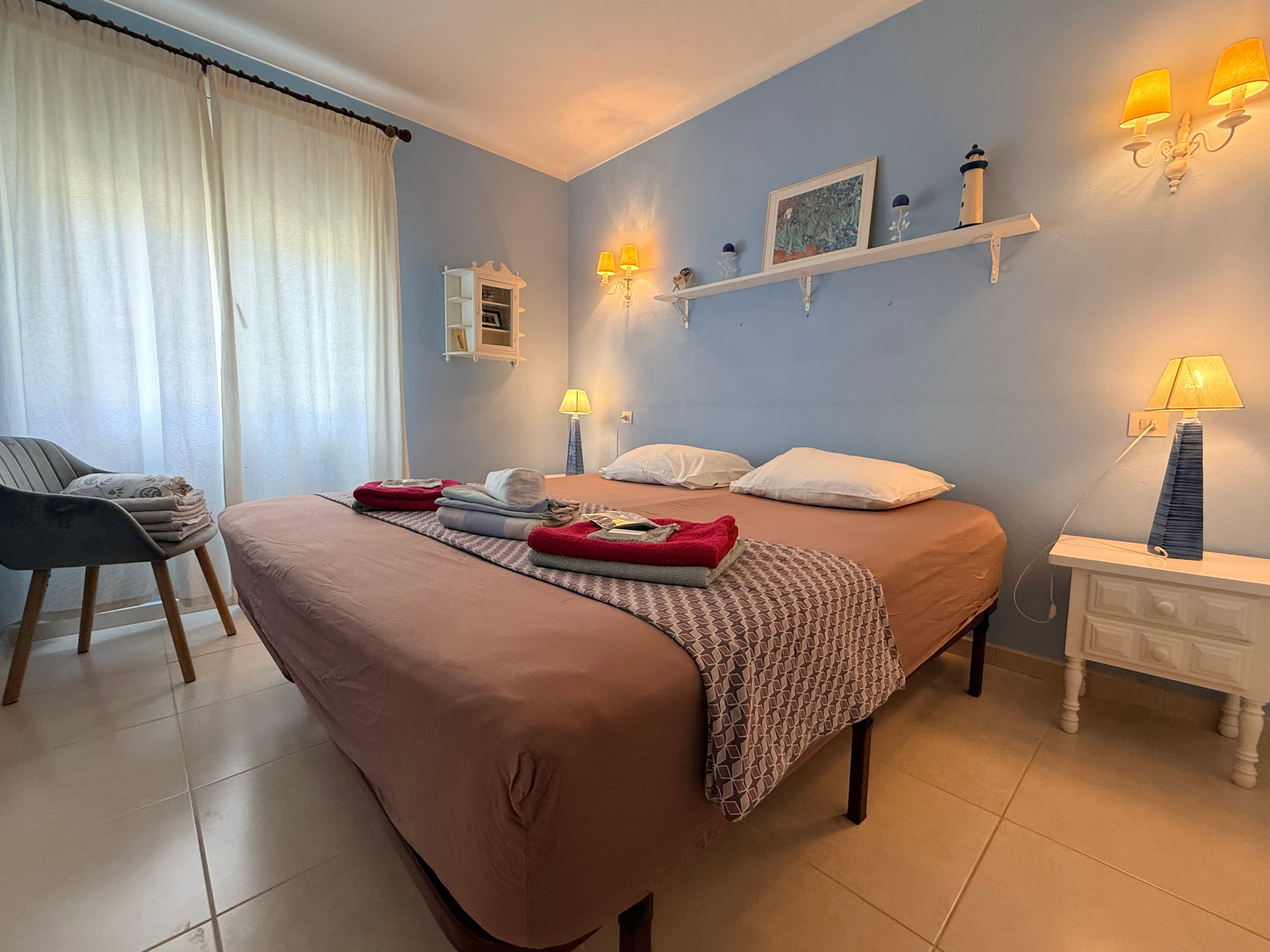 Soothing blue walls and warm ambient lighting define this peaceful bedroom. A spacious bed with fresh linens ensures deep rest.