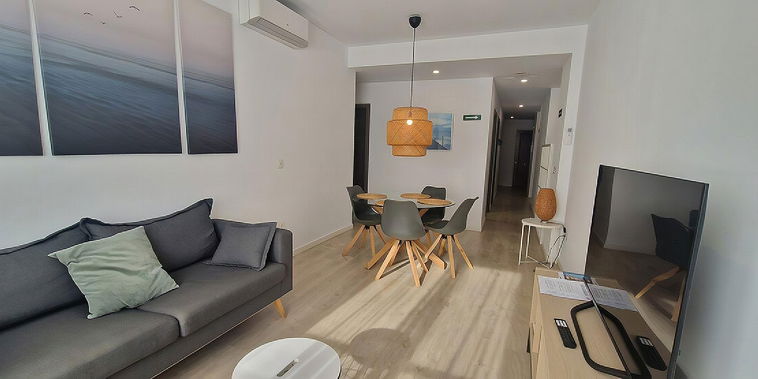 Relax in the bright, modern living area, featuring clean lines, light wood floors, and a stylish woven pendant lamp.