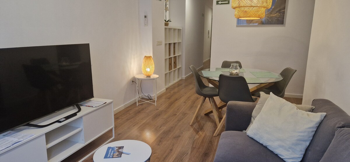 Espacio amplio y luminoso, con mesa para cuatro personas, sofá confortable y aire acondicionado, perfecto para disfrutar de comidas y momentos de relax.