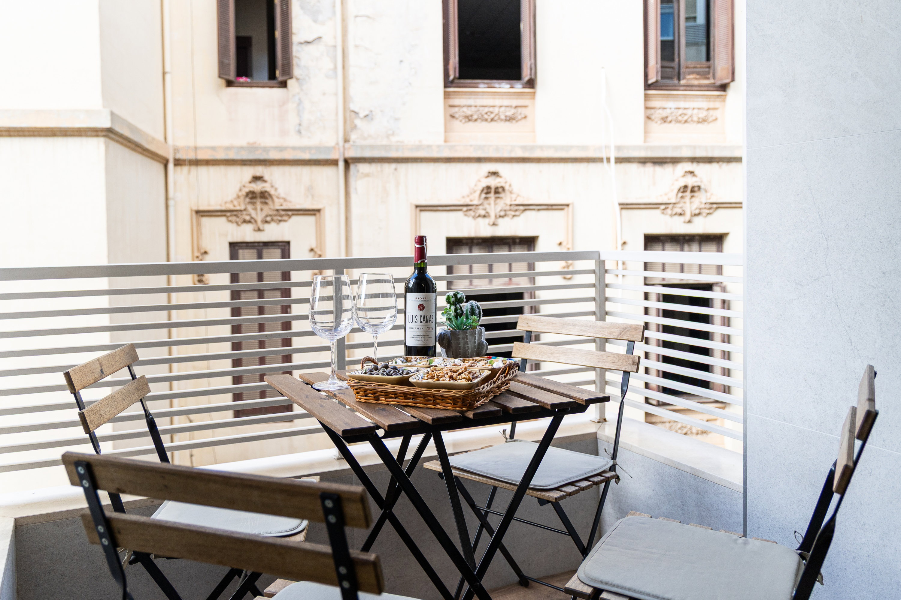 Savor local wine on this elegant balcony. The wooden set overlooks ornate Andalusian architecture. Enjoy a calm outdoor retreat.