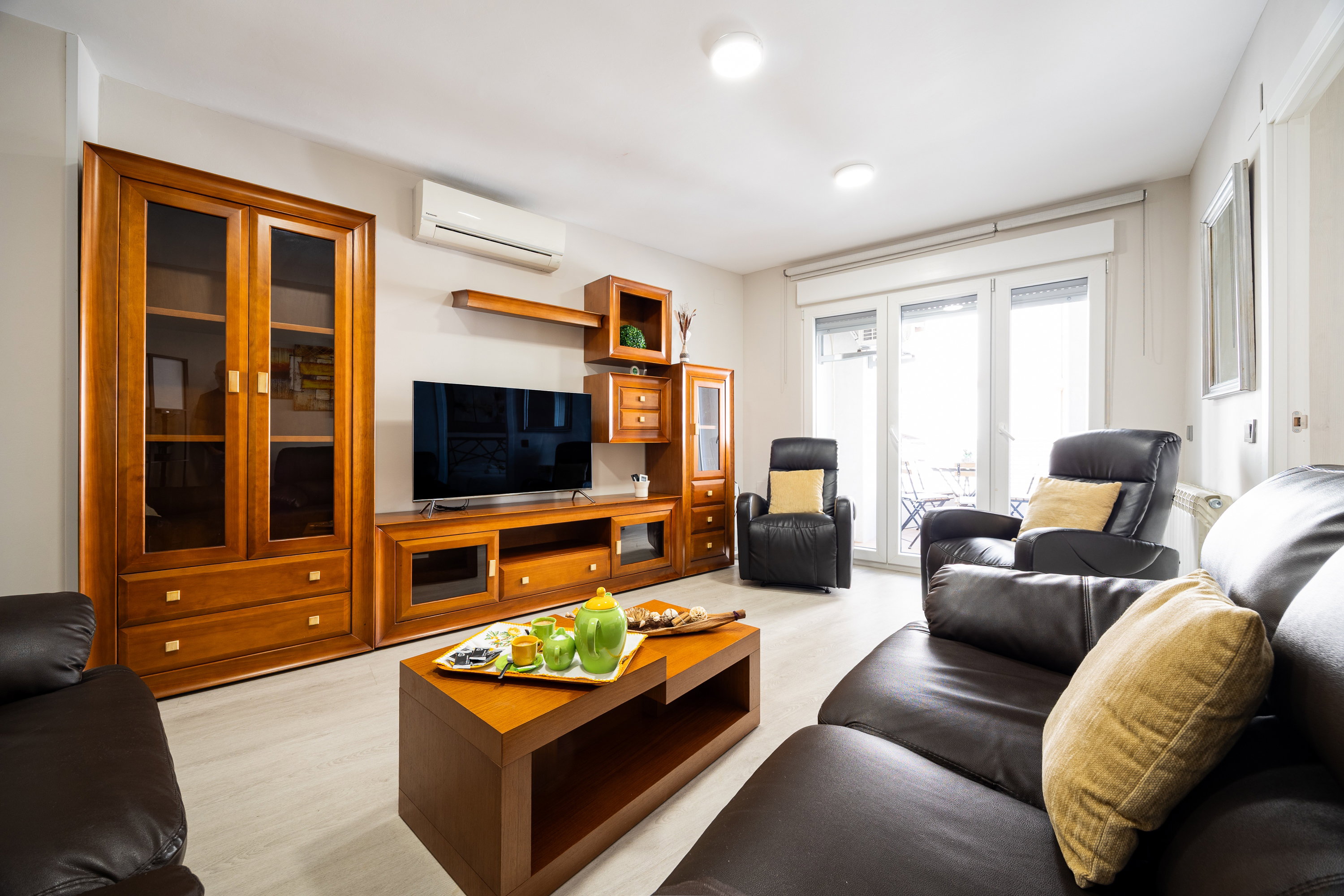 Relax in this bright, elegant living room. Plush leather sofas and rich wood accents form a cozy space near the balcony.