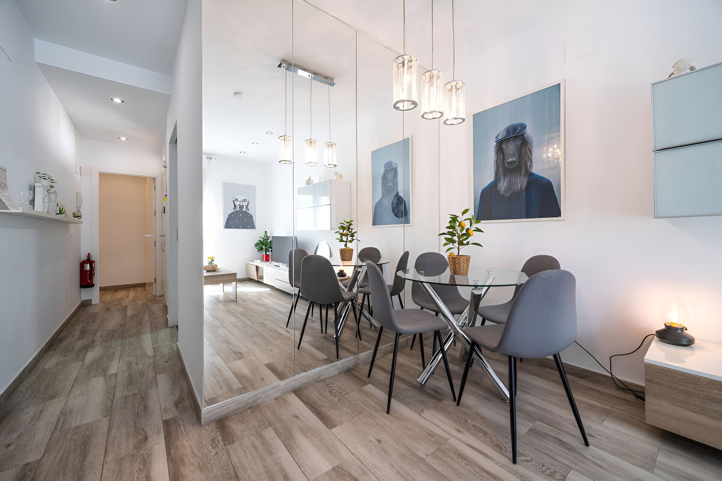 The living room/tv room is open to the dining area, which features a table with four chairs and a large mirror.