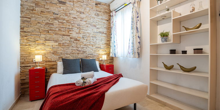 Unwind in this stylish bedroom featuring a rustic stone accent wall, comfortable double bed, and modern air conditioning.