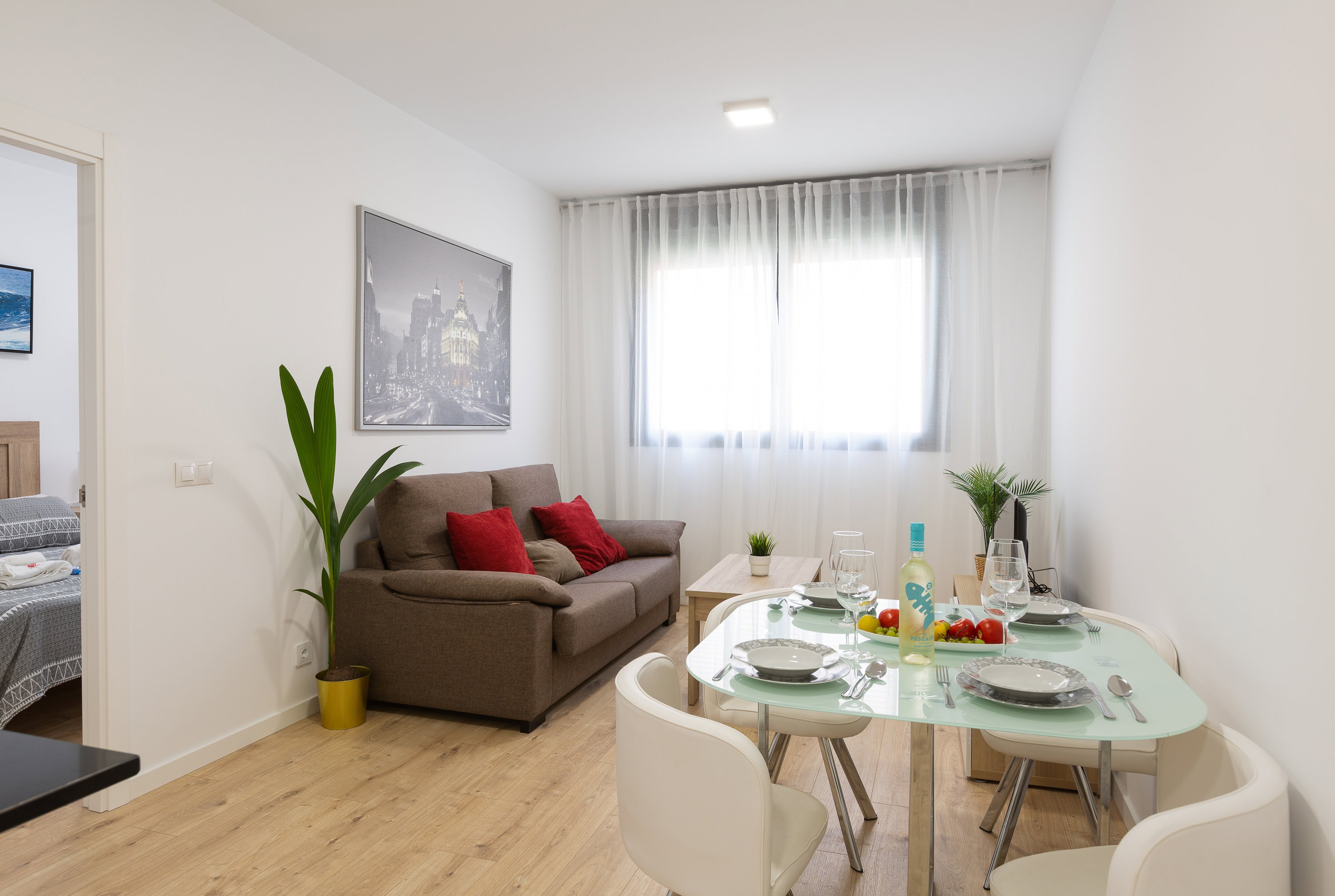 Sunlight fills this bright, modern living space. Unwind on the plush sofa or dine at the elegant glass table set for four.