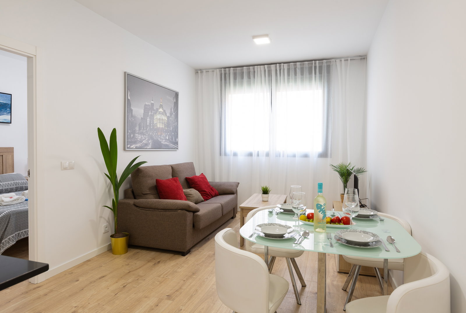 Sunlight fills this bright, modern living space. Unwind on the plush sofa or dine at the elegant glass table set for four.
