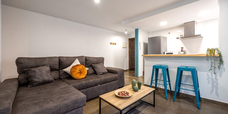 Relax in this modern open-plan living area featuring a plush sectional sofa and a convenient breakfast bar.