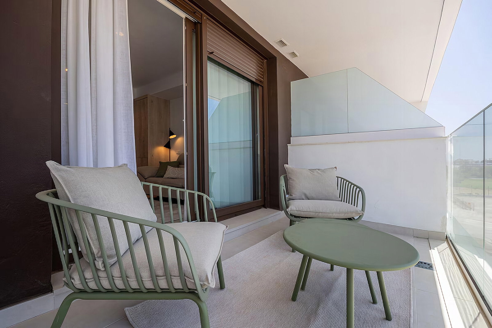 Enjoy the bright private terrace with modern green lounging chairs and a sleek glass balustrade. A perfect spot to relax outdoors.