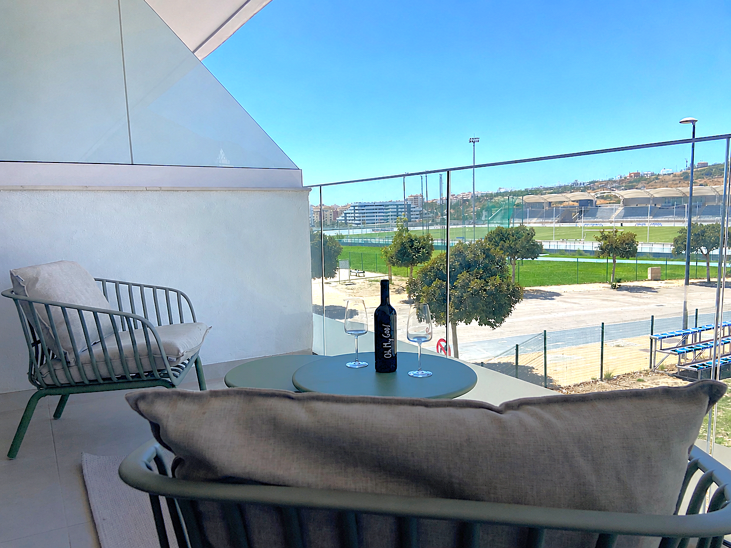 Unwind on the modern private terrace featuring plush seating. Enjoy wine while taking in sunny views of vibrant green spaces.