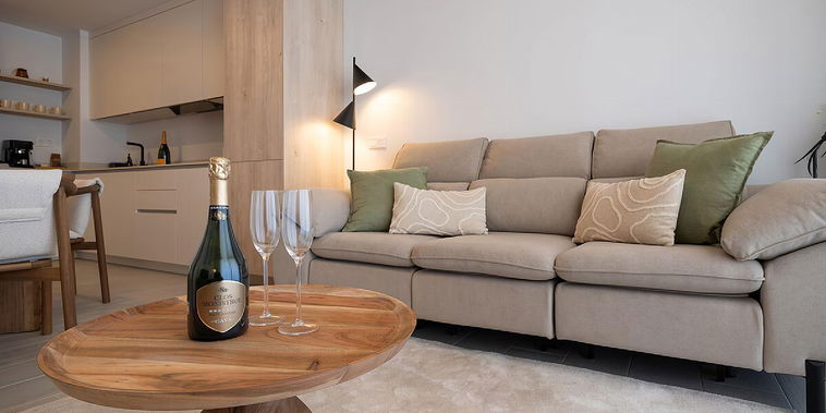 Relax on the plush sofa in this elegant, open-plan living space. Champagne awaits on a striking wooden coffee table.