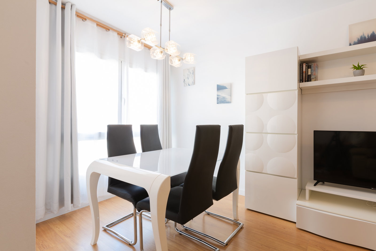 Enjoy meals in this bright dining area featuring sleek modern seating, warm wood floors, and chic lighting.