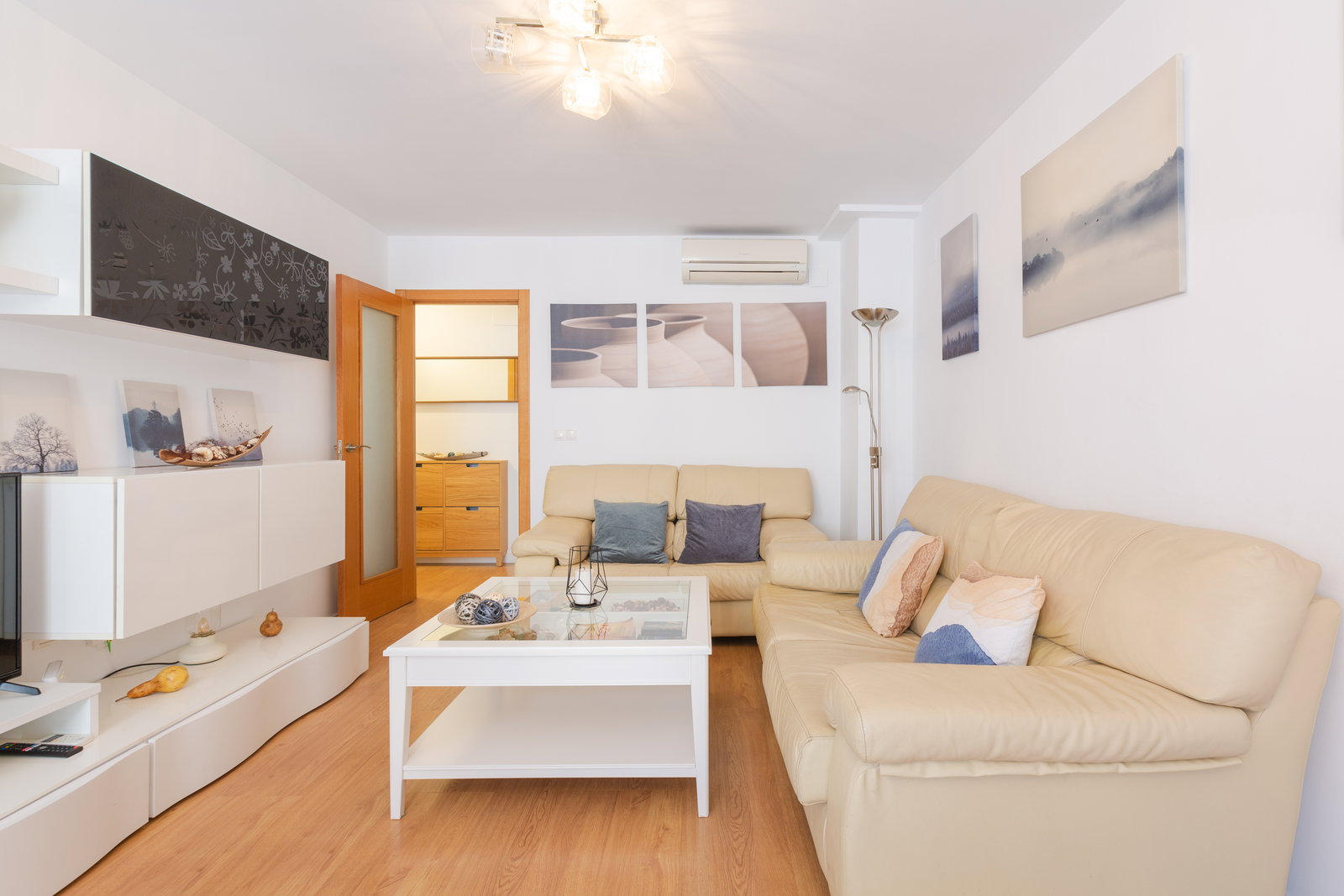 Relax in the bright living room featuring comfortable leather sofas, modern decor, and refreshing air conditioning.