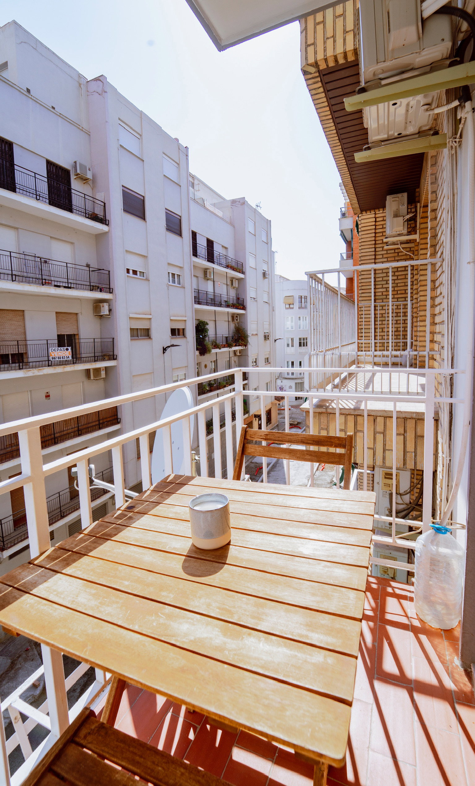 small balcony with  table and two chairs. A satellite dish is attached to the balcony.