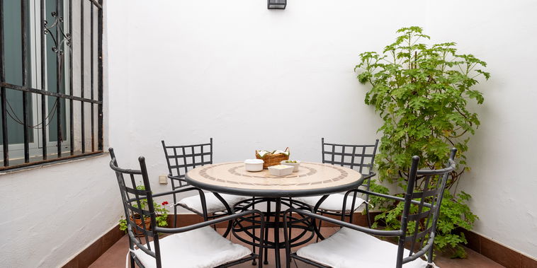 Unwind in a serene, private Andalusian courtyard. A mosaic table and wrought-iron chairs invite elegant al fresco dining.