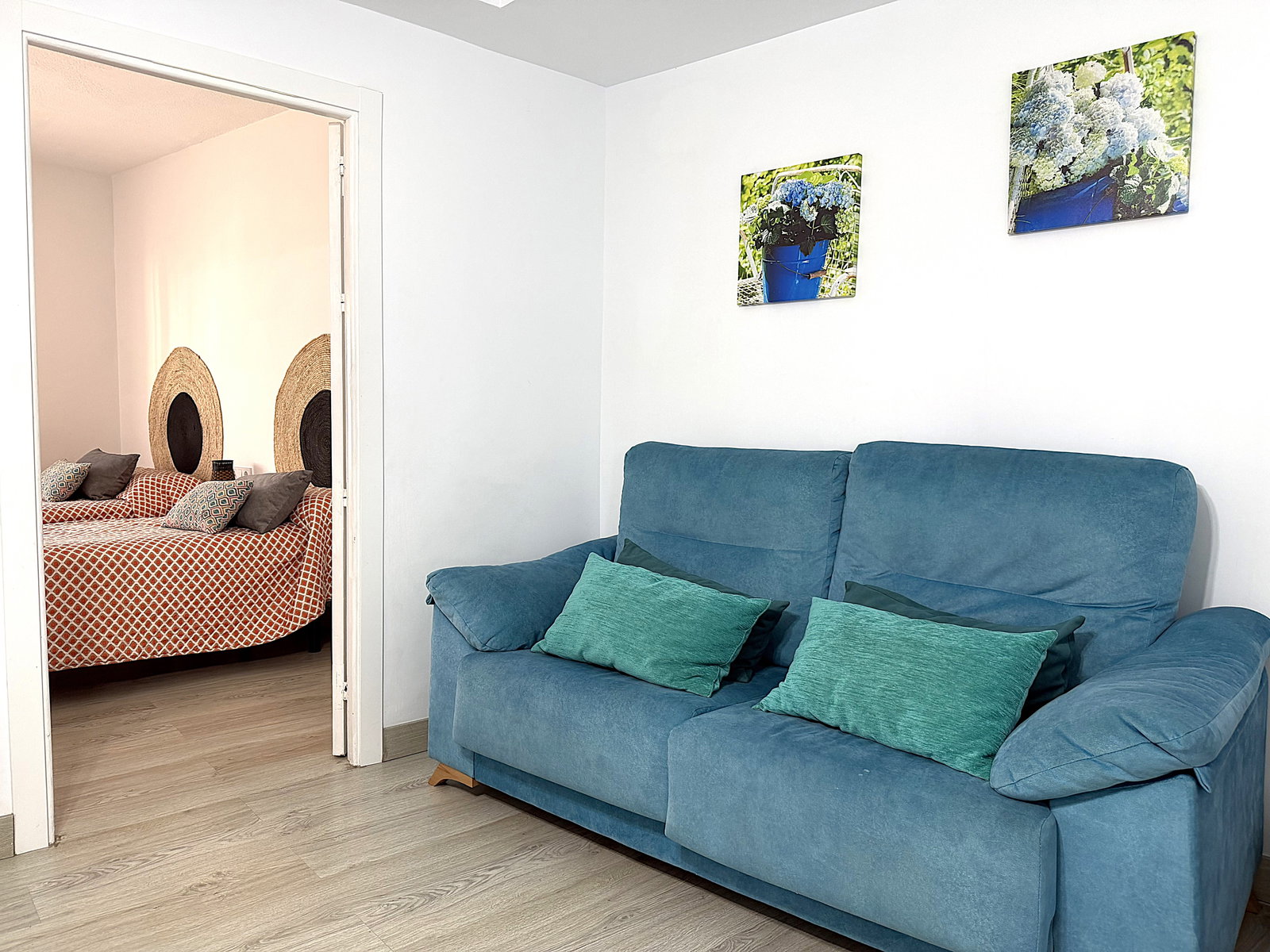 Relax on the plush sofa in this bright living area. An adjacent twin bedroom offers charming woven decor and serene comfort.