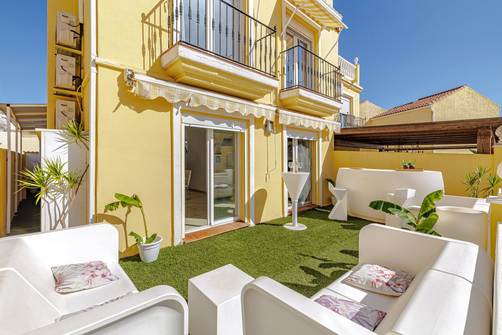 Relax on the sunlit private terrace featuring stylish contemporary lounge seating and bright Mediterranean architecture.