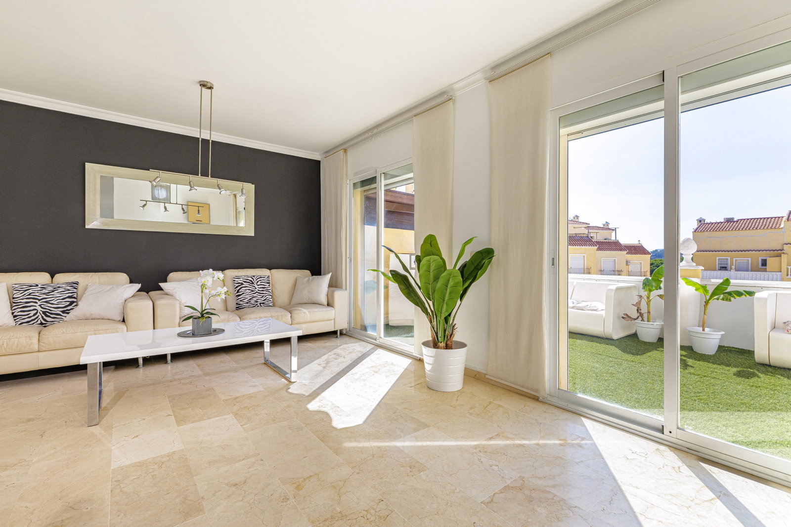 Unwind in this bright, elegant living room offering seamless access to a sunny terrace with stylish outdoor seating.
